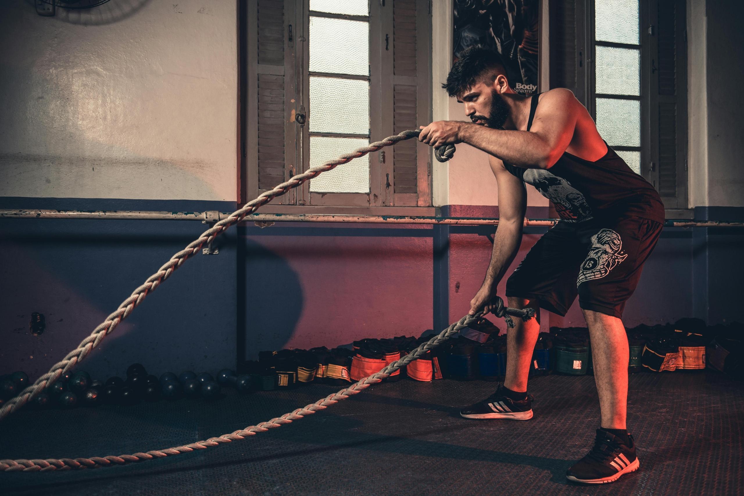 A man pushing himself in the gym with the heavy ropes.