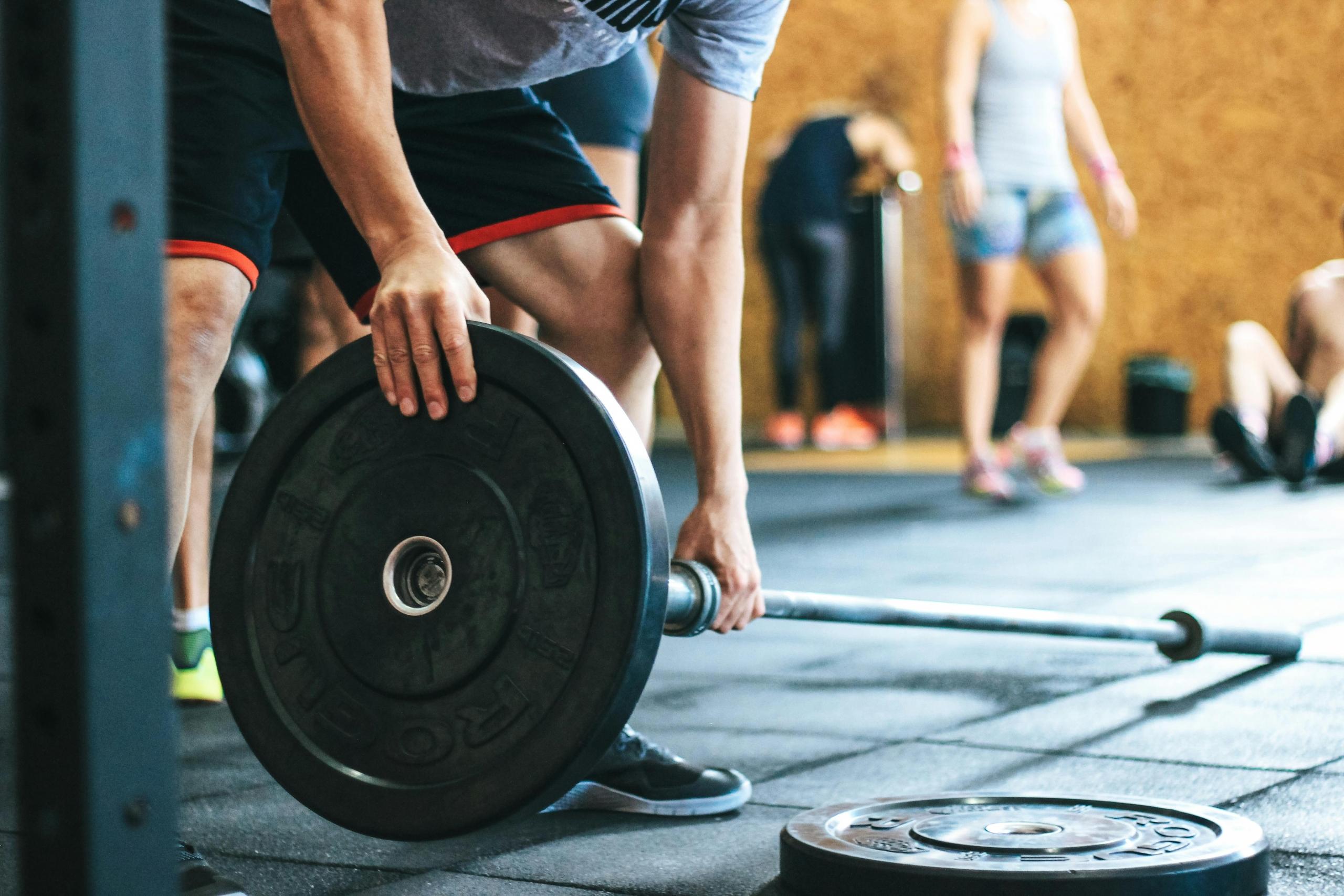 An athlete setting up his equipment for some bent over rows