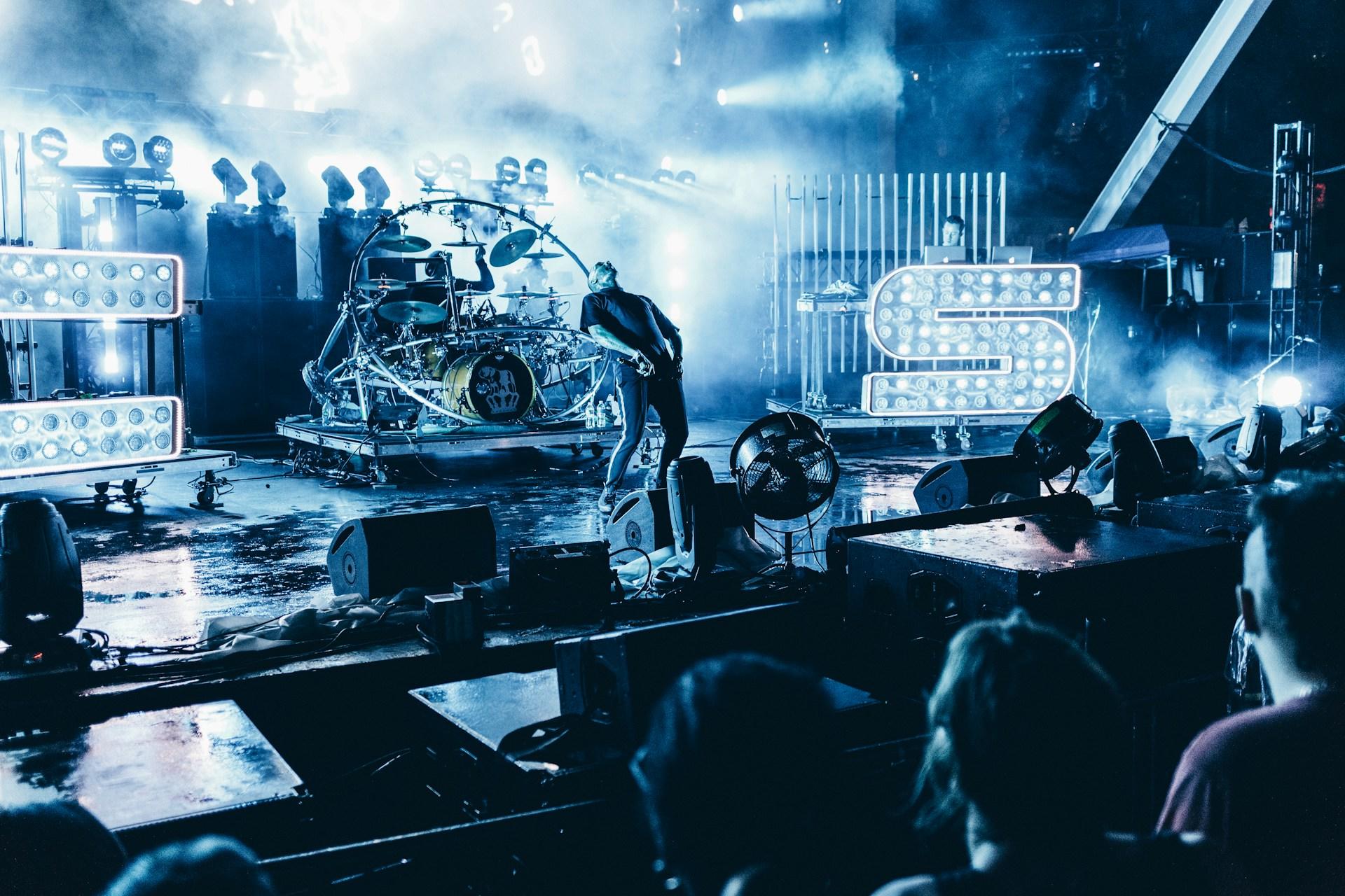A singer on a stage with giant blue lights, singing in a concert venue