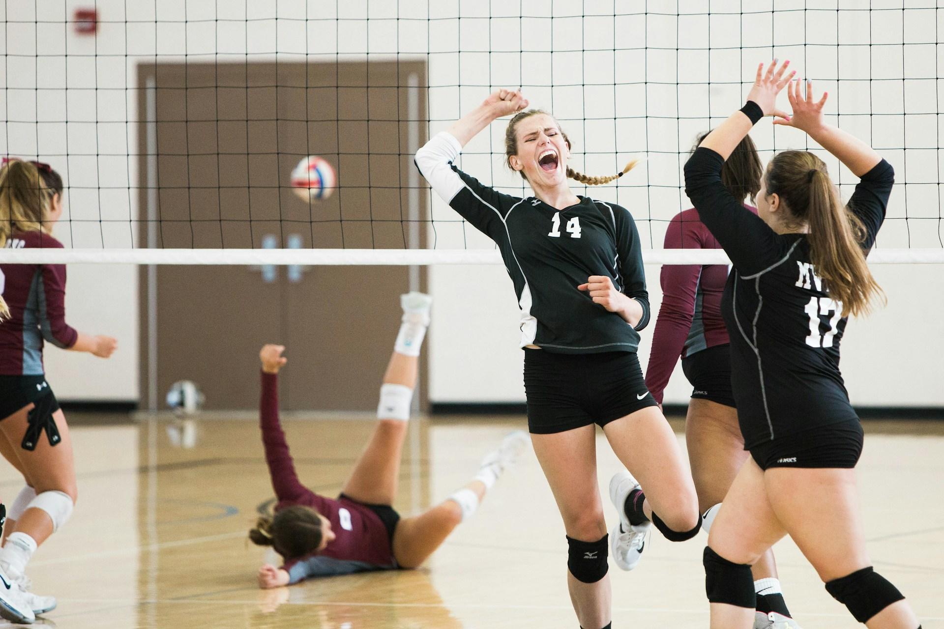 Volleyball players celebrating a spike on the court.