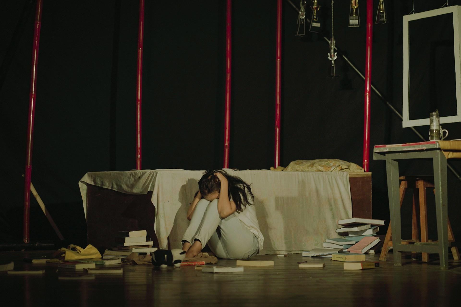 An actress crying and scared in a scene on stage.