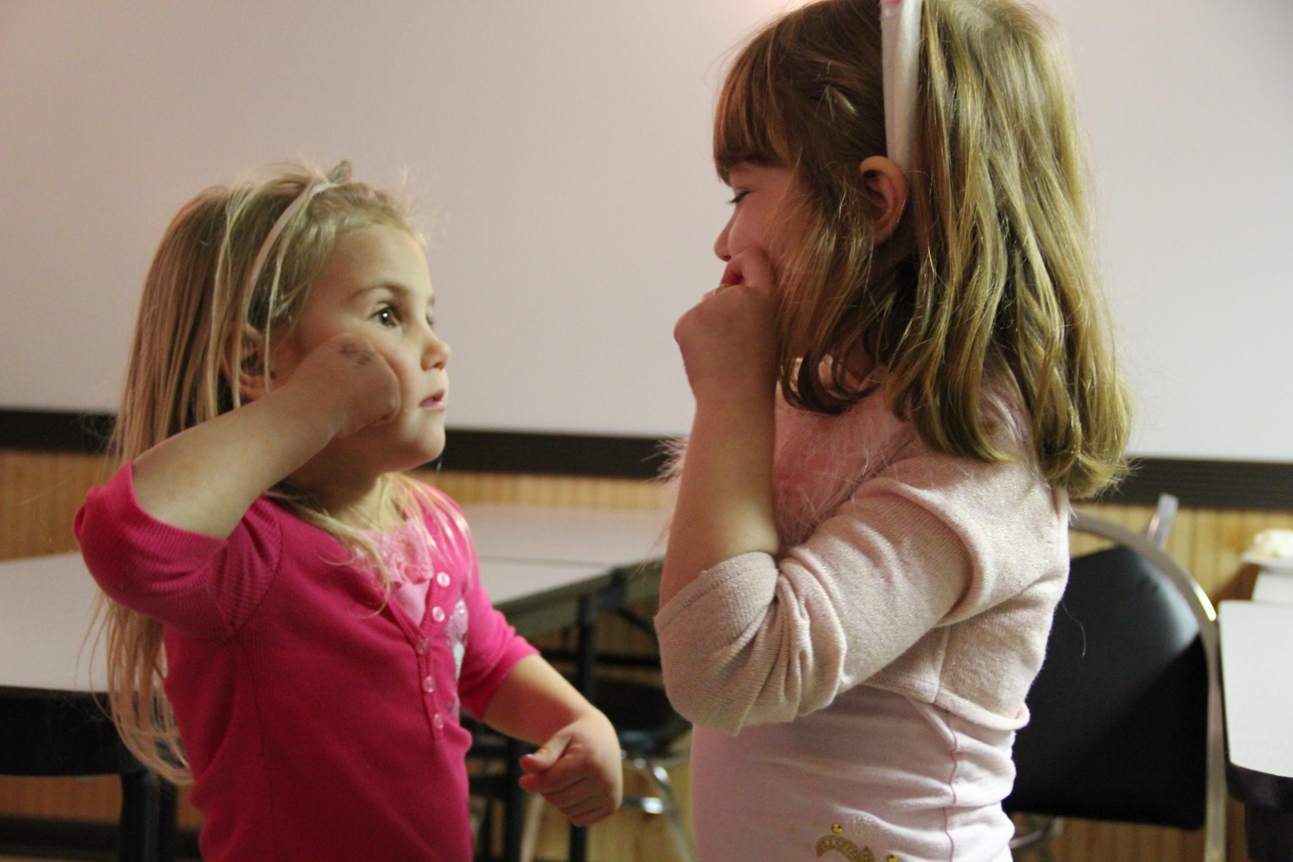Two toddlers learning sign language together.