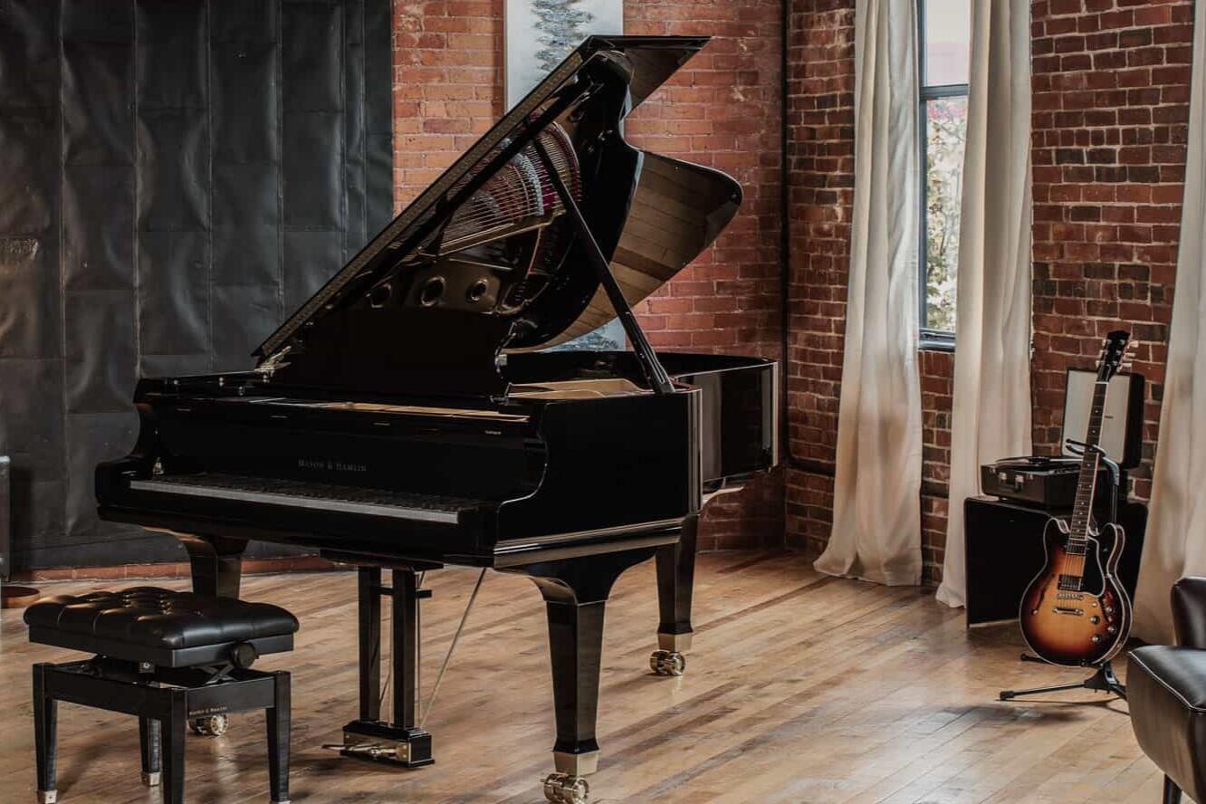 Mason and Hamlin Model BB grand piano with its lid open in a brick-walled studio.