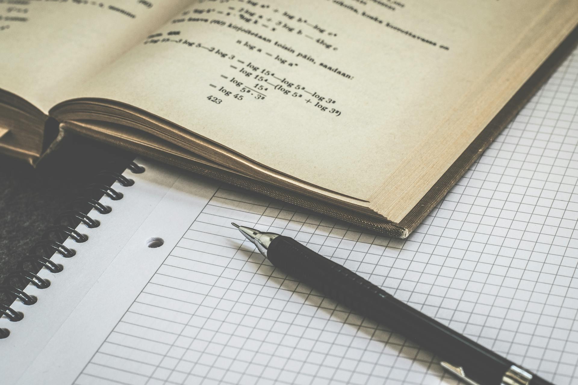 Squared paper and a math textbook with pen.