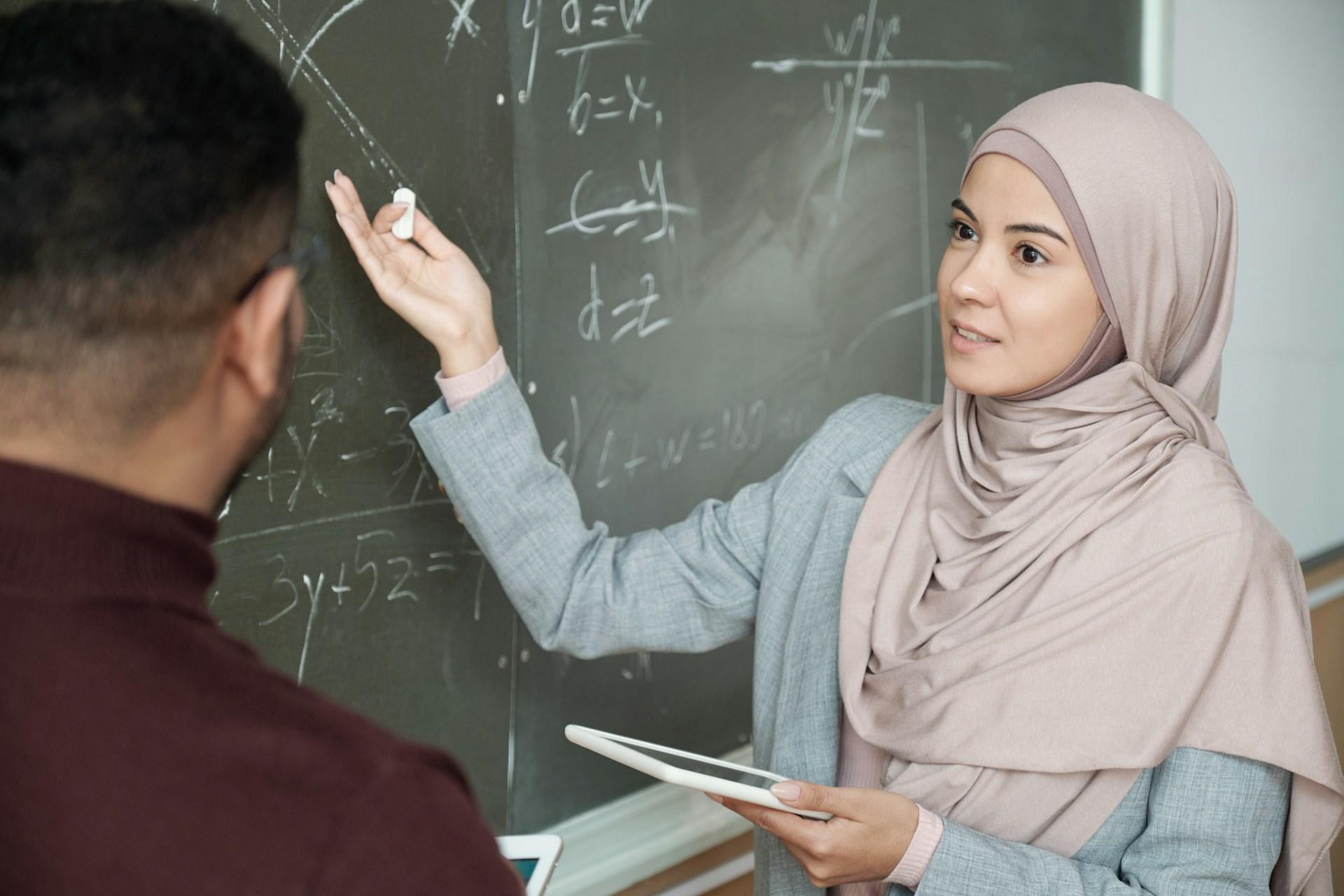 A math tutor and student solving a problem on the chalkboard.