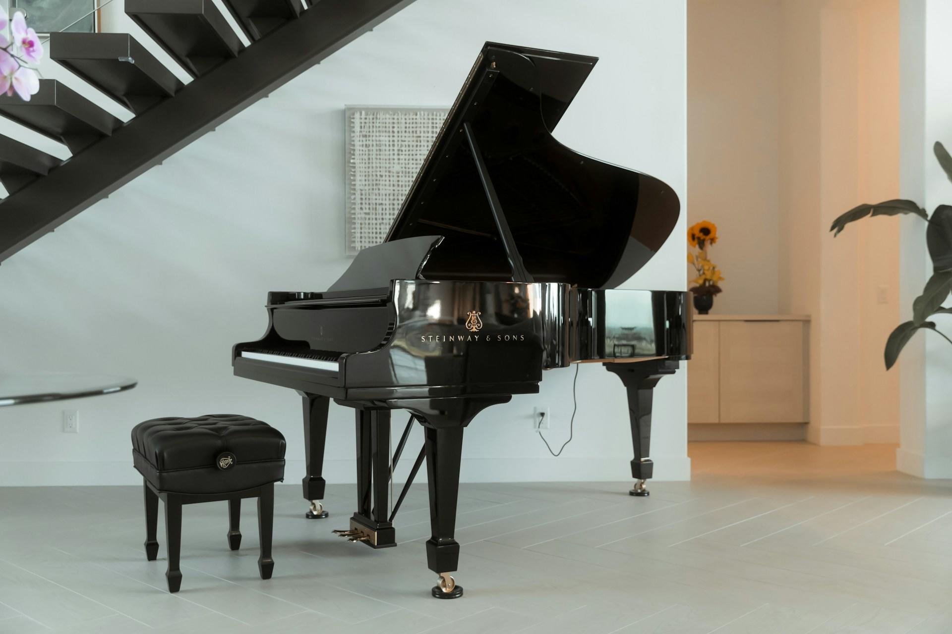 A Steinway & Sons piano under a set of stairs.