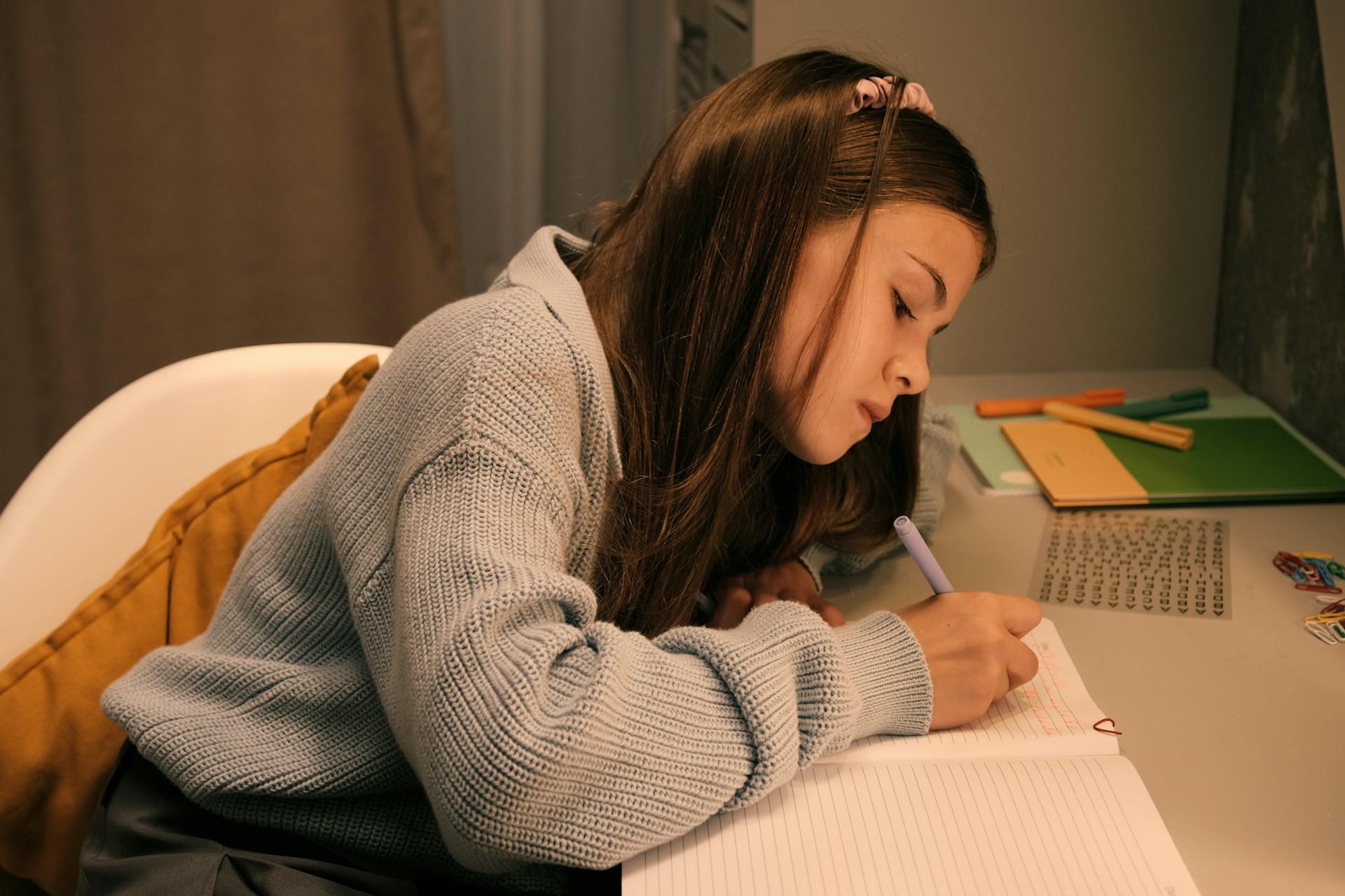 A girl writing in a notebook at her desk.