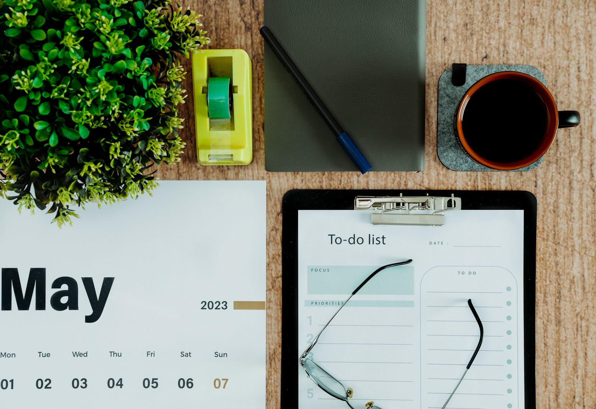 A calendar, to do list, and coffee on a desk.
