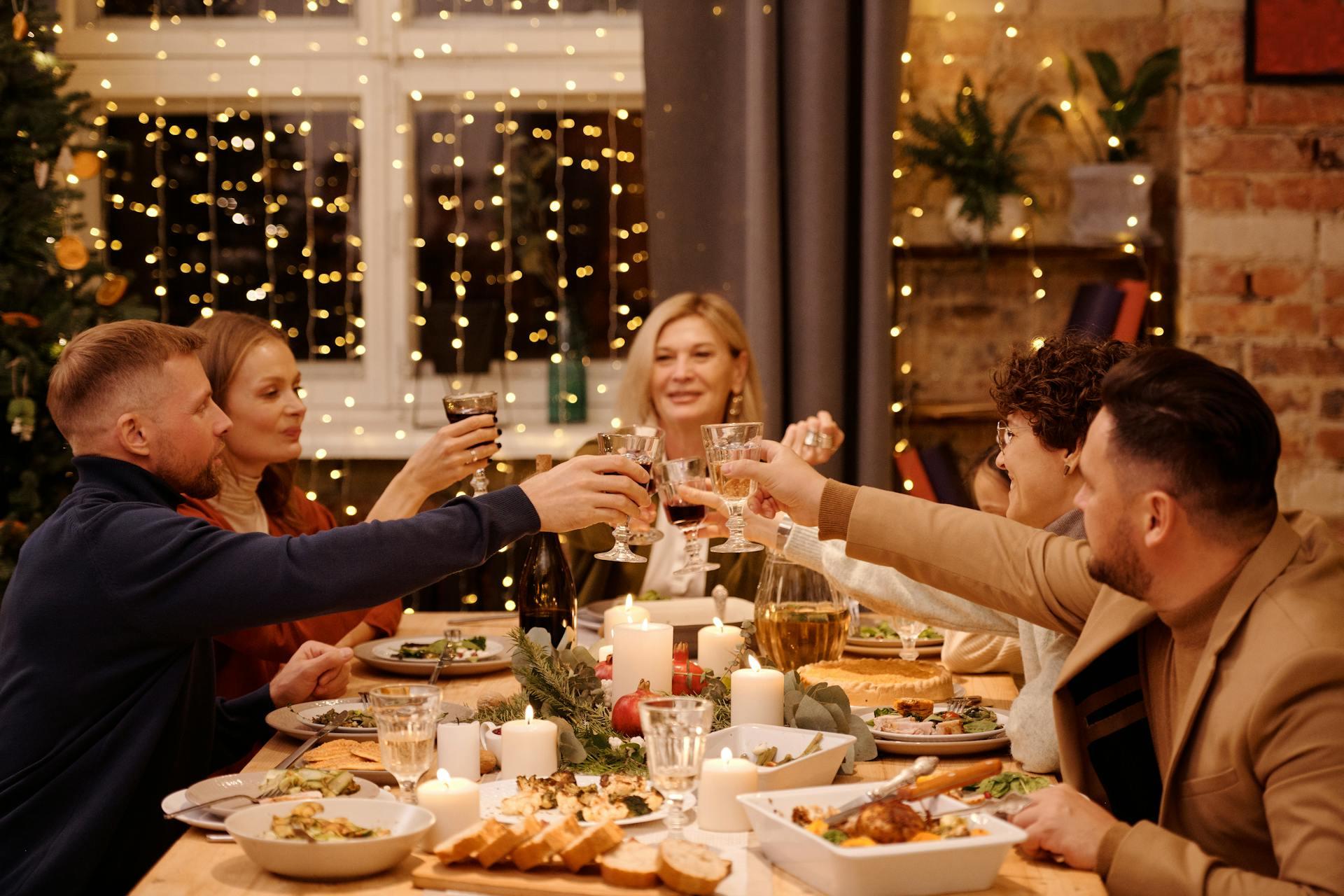 Five people toasting at the table while eating dinner.