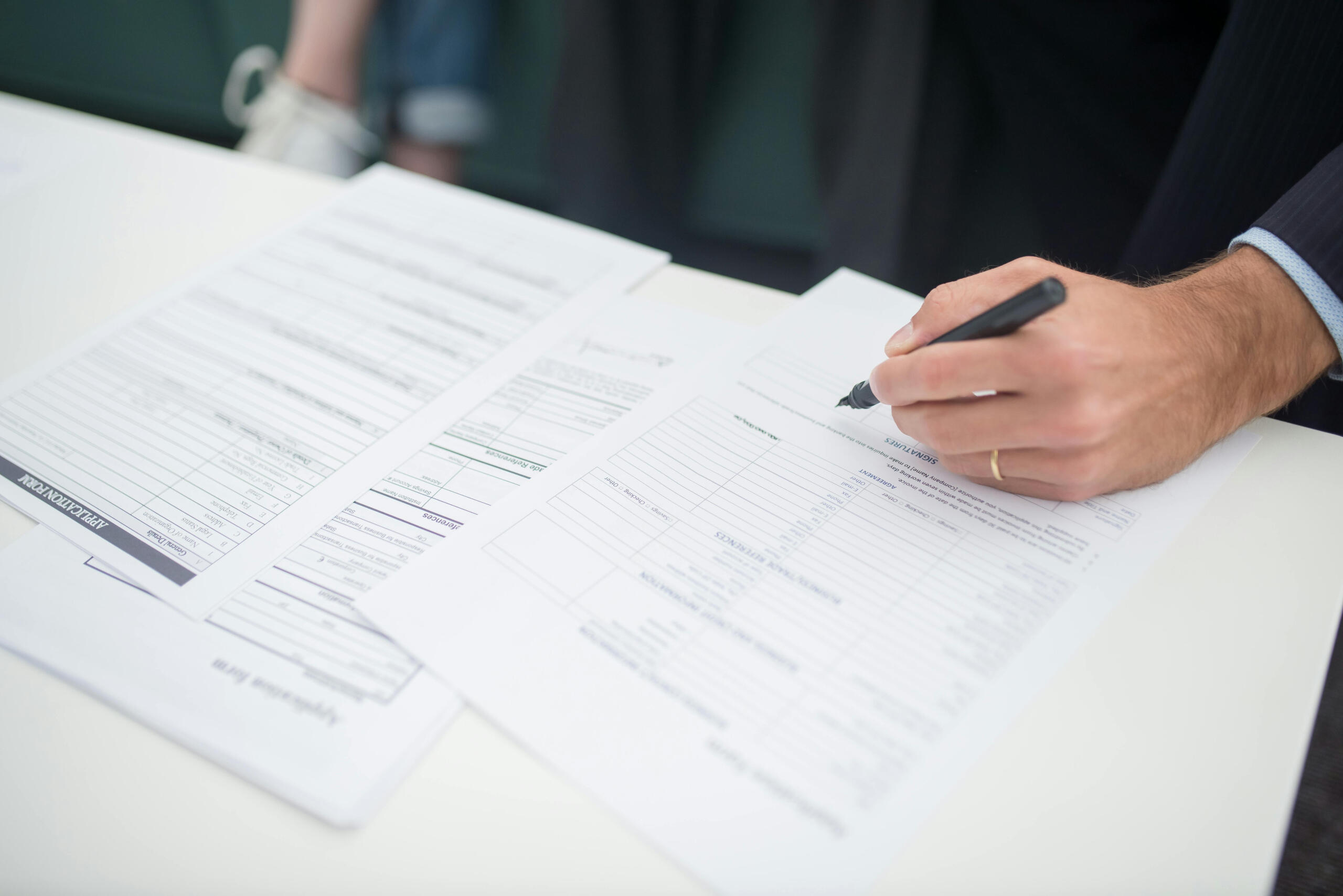 Hand with pen on documents on desk