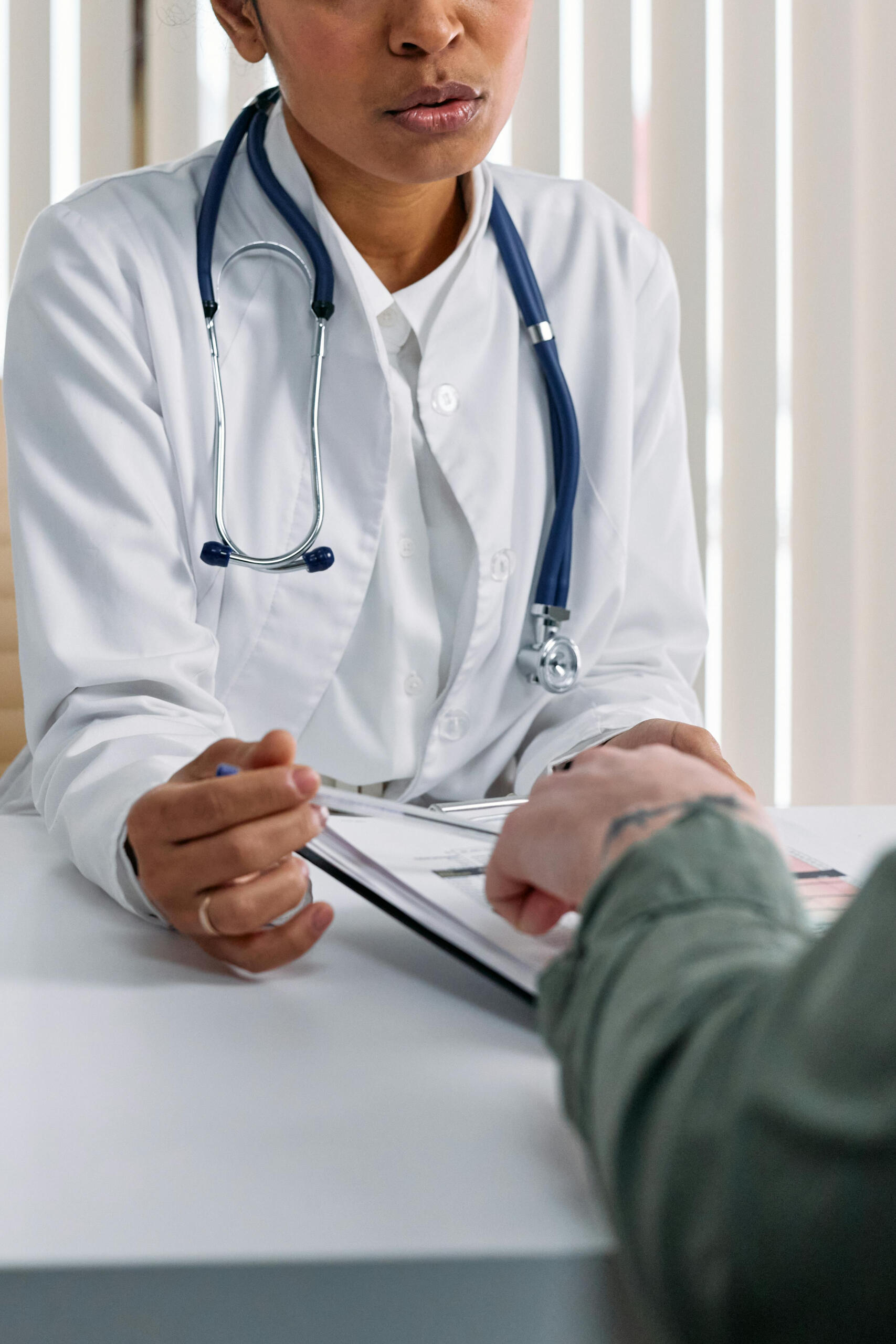 Hands of doctor and patient on table
