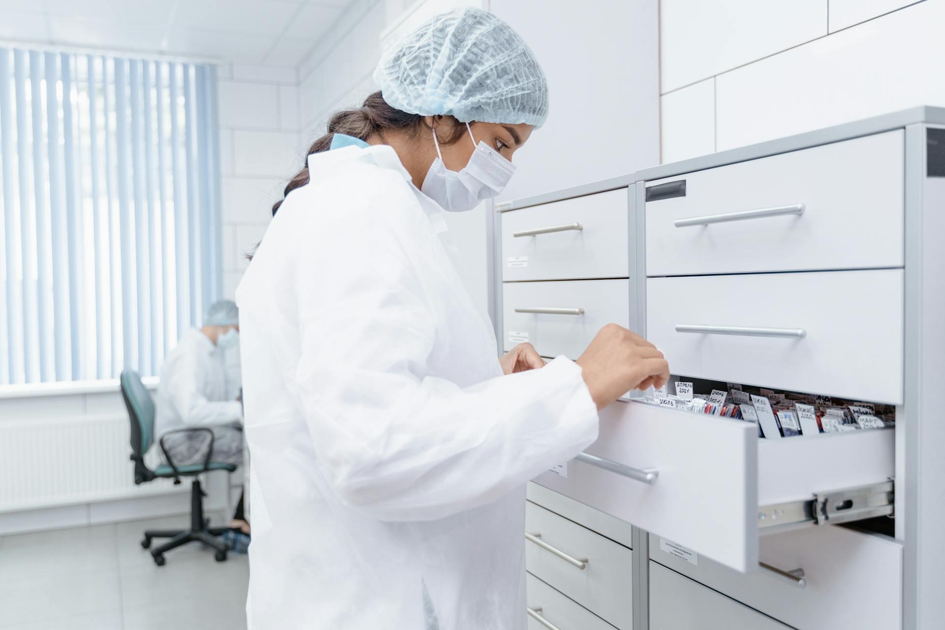 A lab assistant picking out a file in a file cabinet.