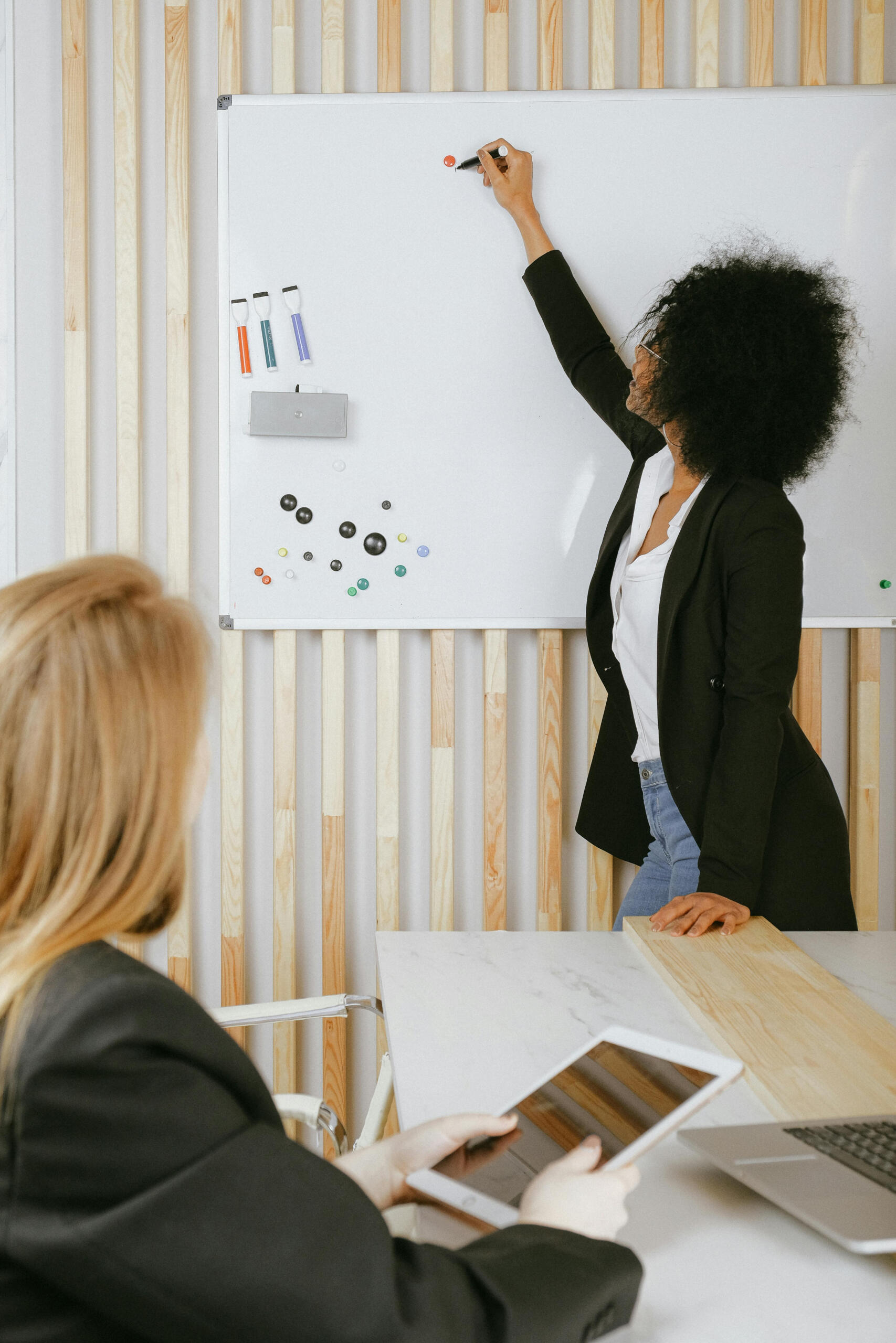 Woman writing on a whiteboard.