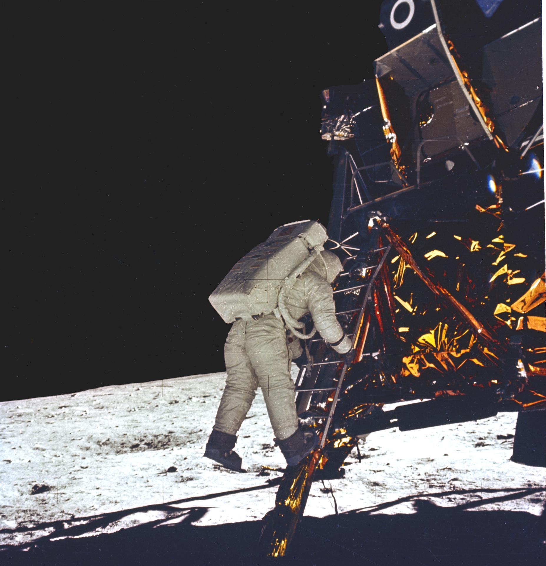 A photo of Buzz Aldrin in his space suit descending a ladder from the Lunar Module to step foot on the moon.