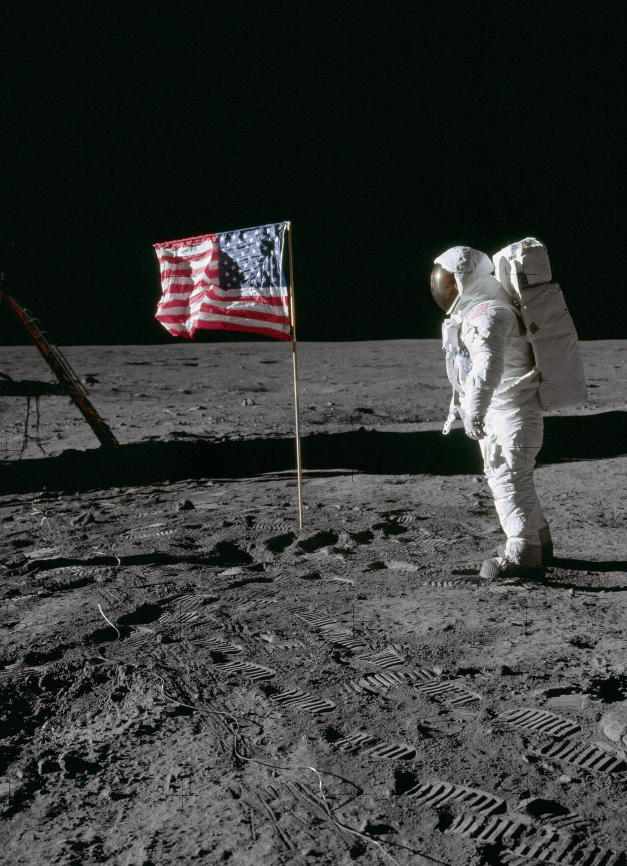 A photo of Buzz Aldrin in his space suit on the surface of the moon with the planted American flag.