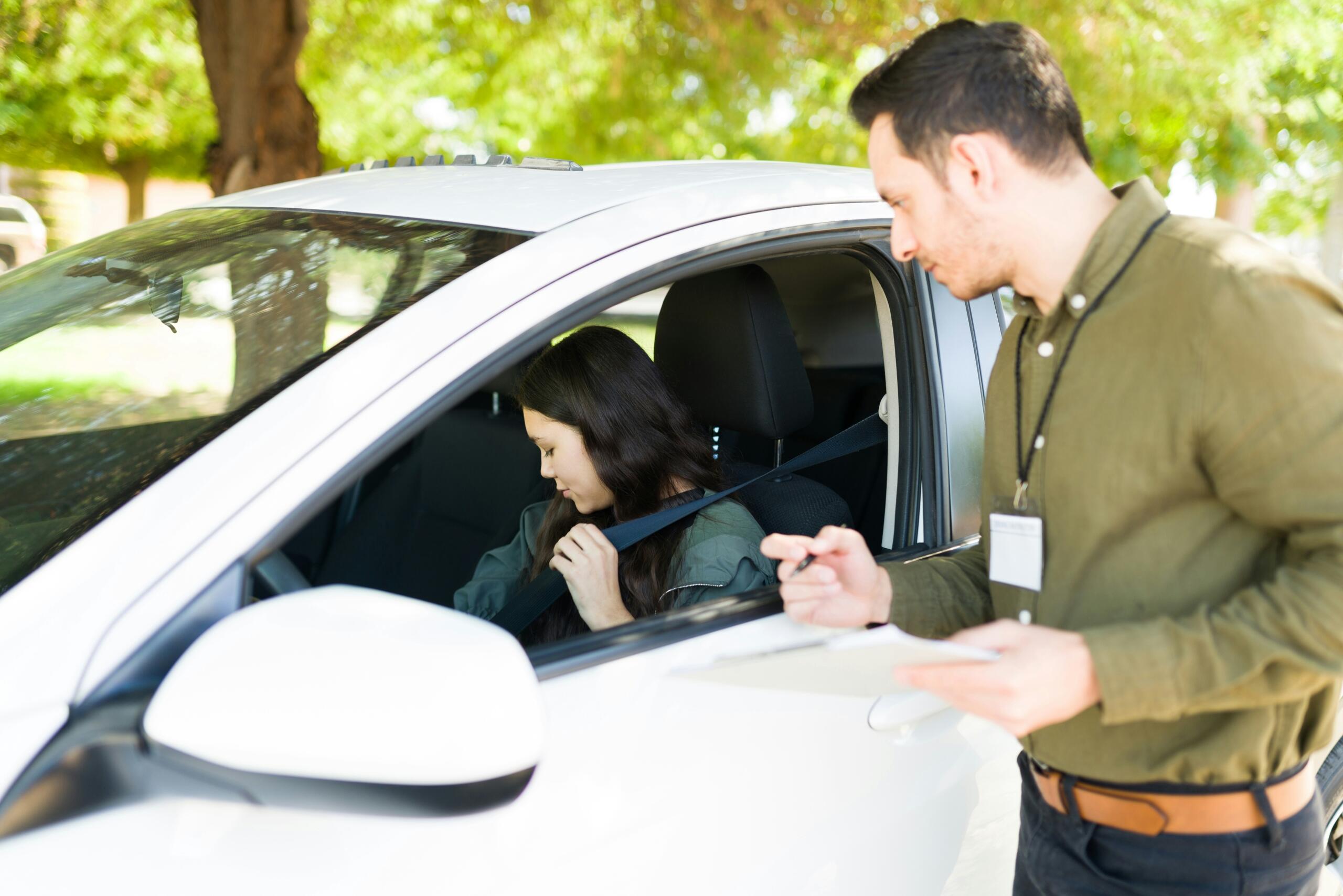 A student driving in the car while her instructor gives her lessons.