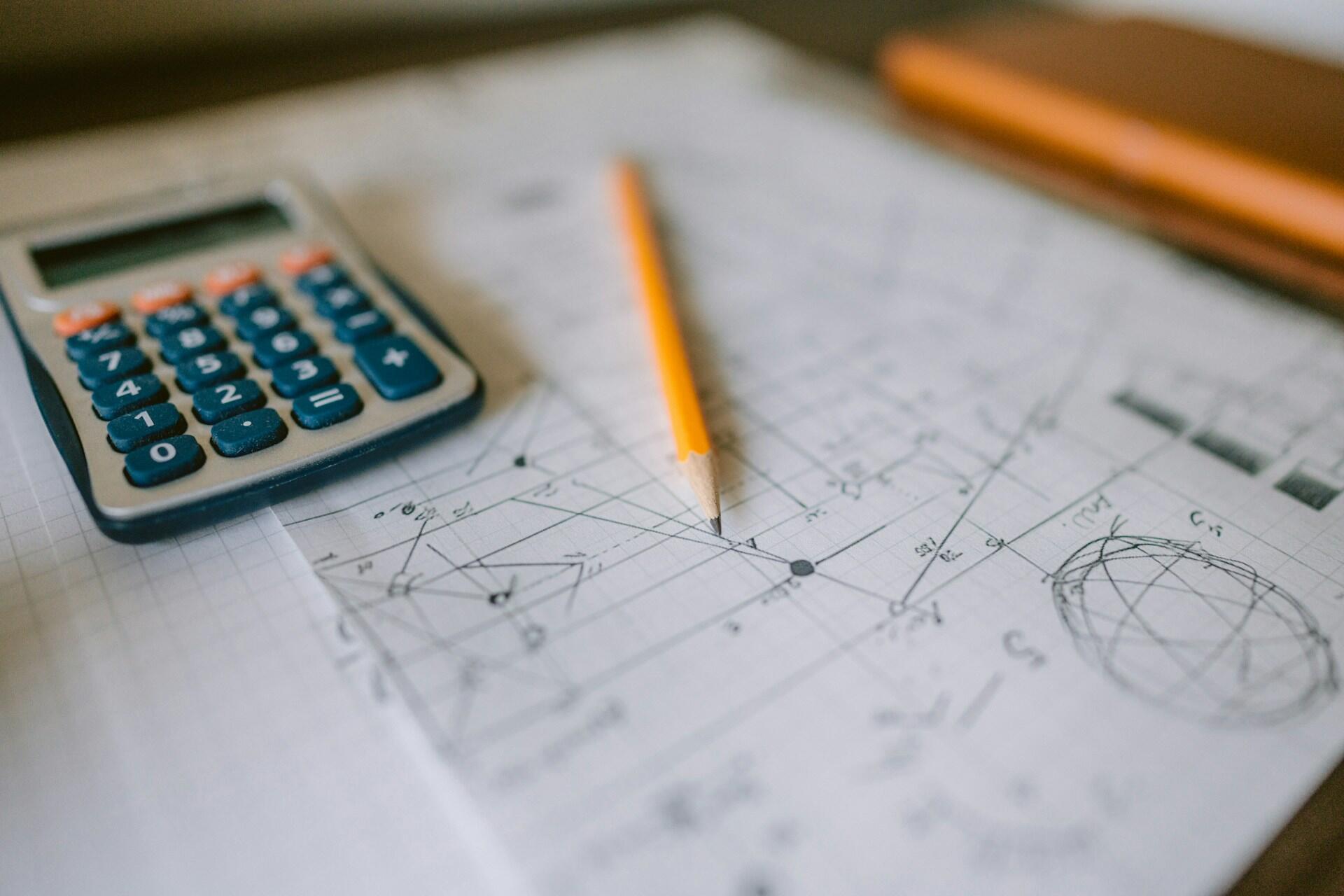 A calculator and pencil on a piece of paper with calculus equations.