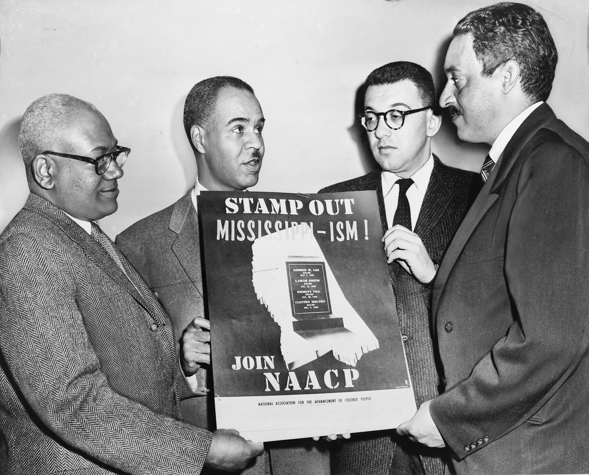 Four important leaders in the NAACP in 1956 hold a poster against racial bias in Mississippi