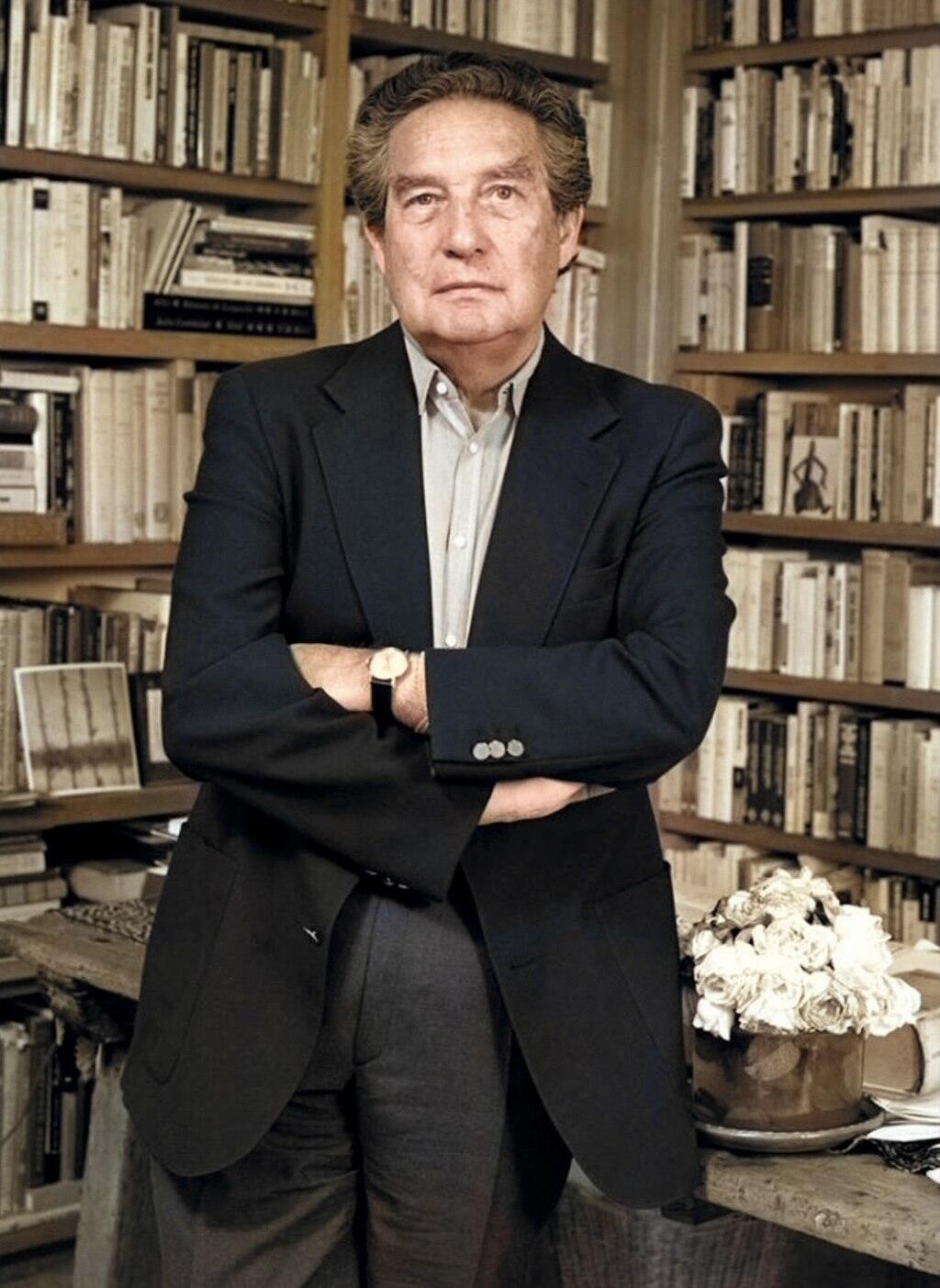 Octavio Paz sitting on a desk posing.