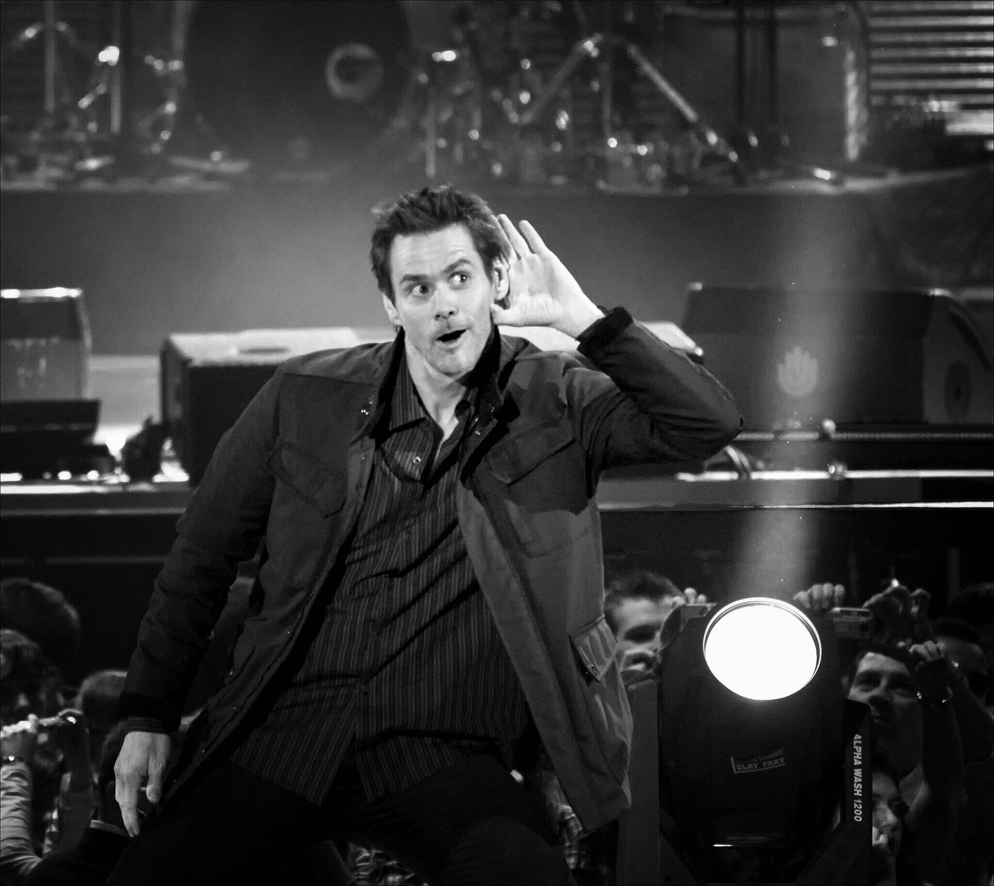 A black and white photo of Jim Carrey with his hand up to his ear.