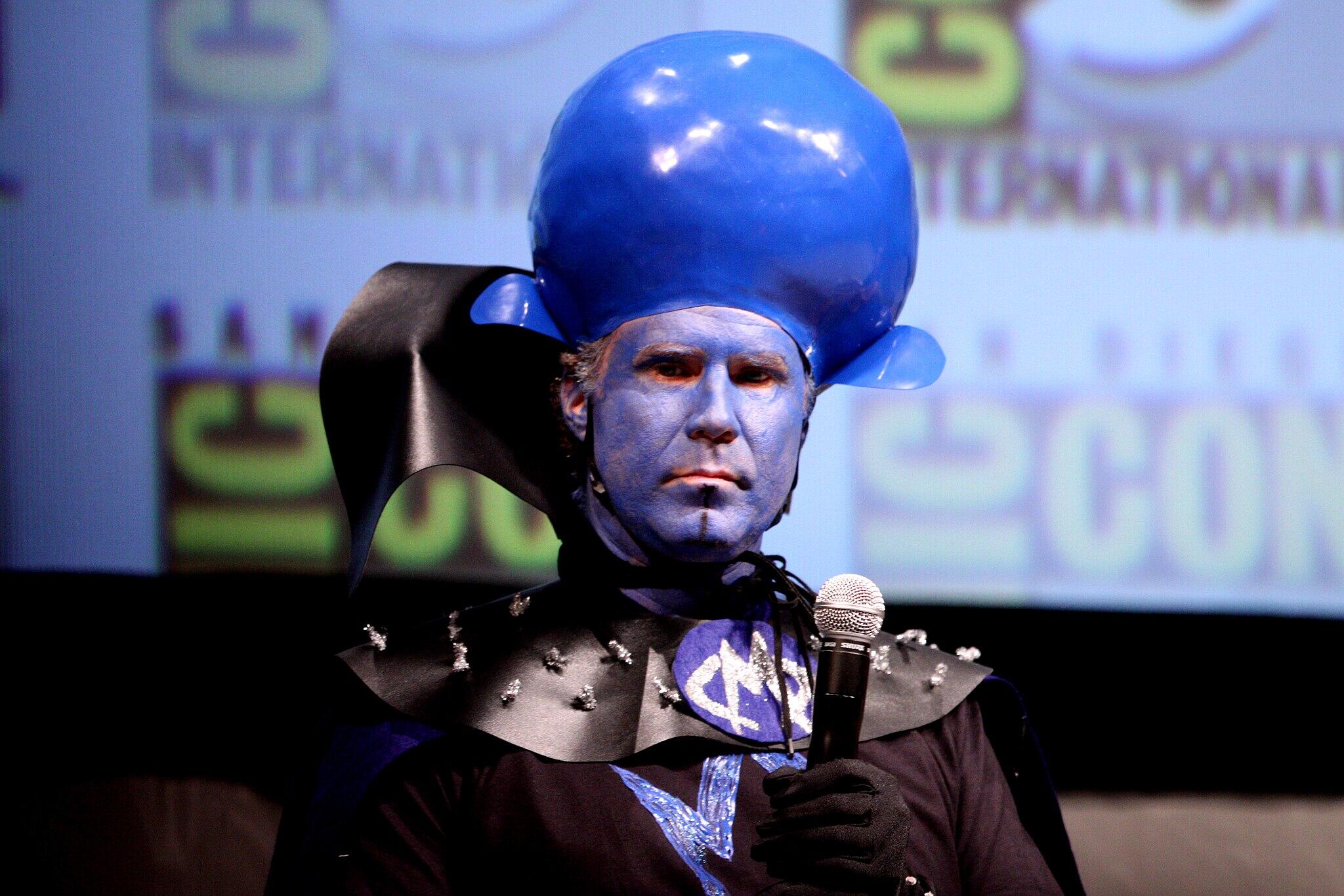 Will Ferrell in a blue costume holding a microphone.