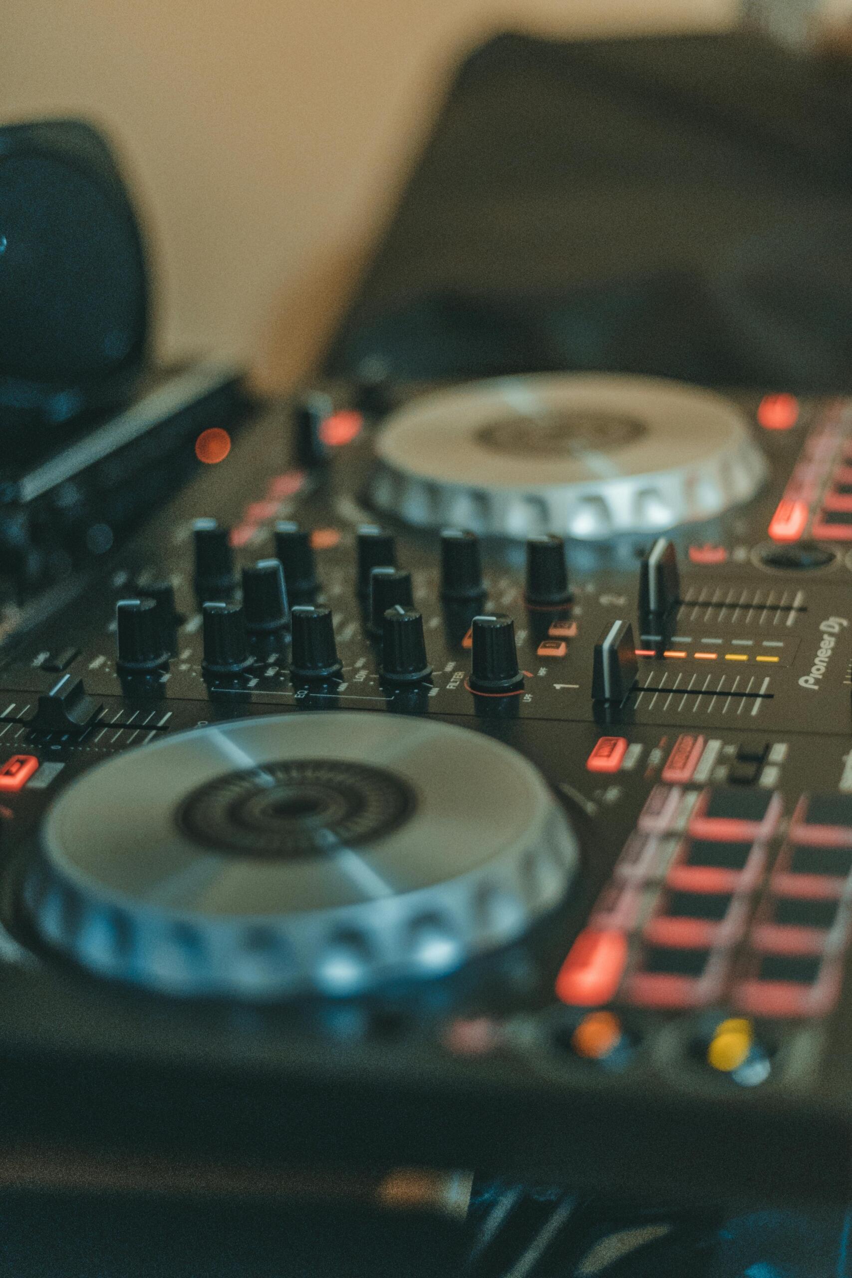 A black DJ controller with various knobs, buttons, and jog wheels, set up for mixing music.