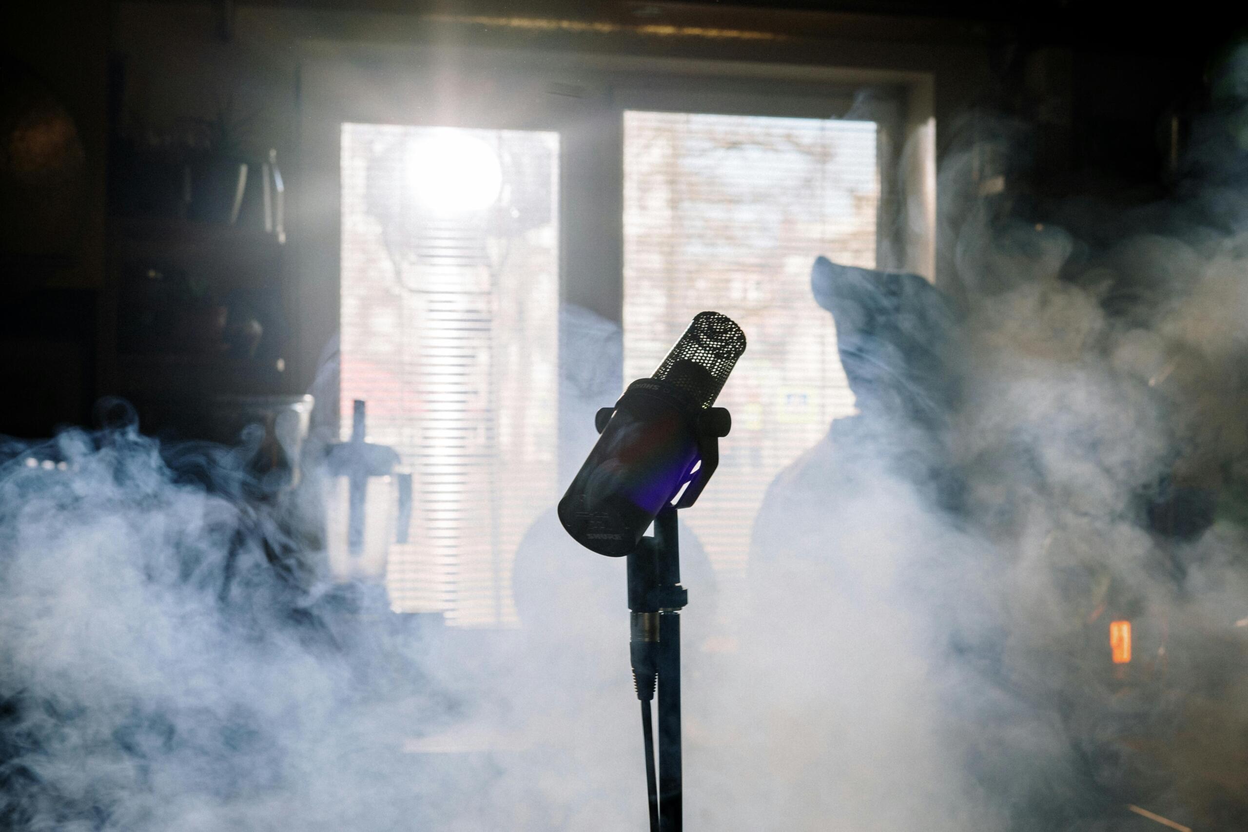 Black microphone with a stand surrounded by white smoke, creating a dramatic effect.