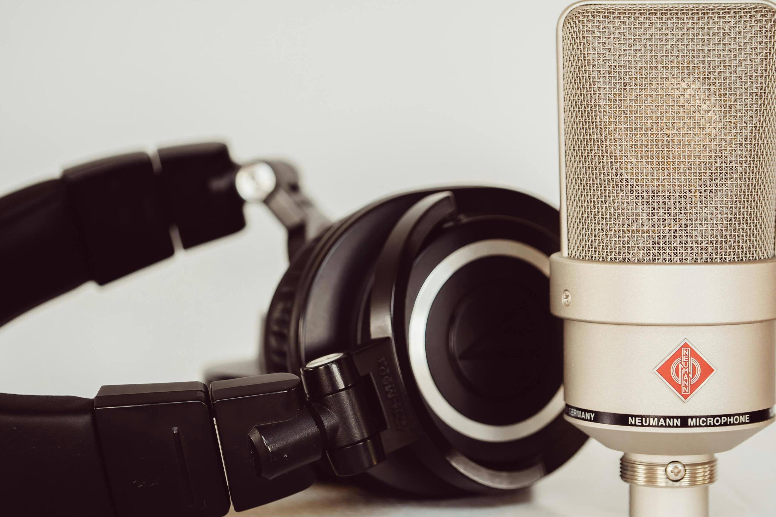 A gray condenser microphone mounted on a stand in a recording studio.