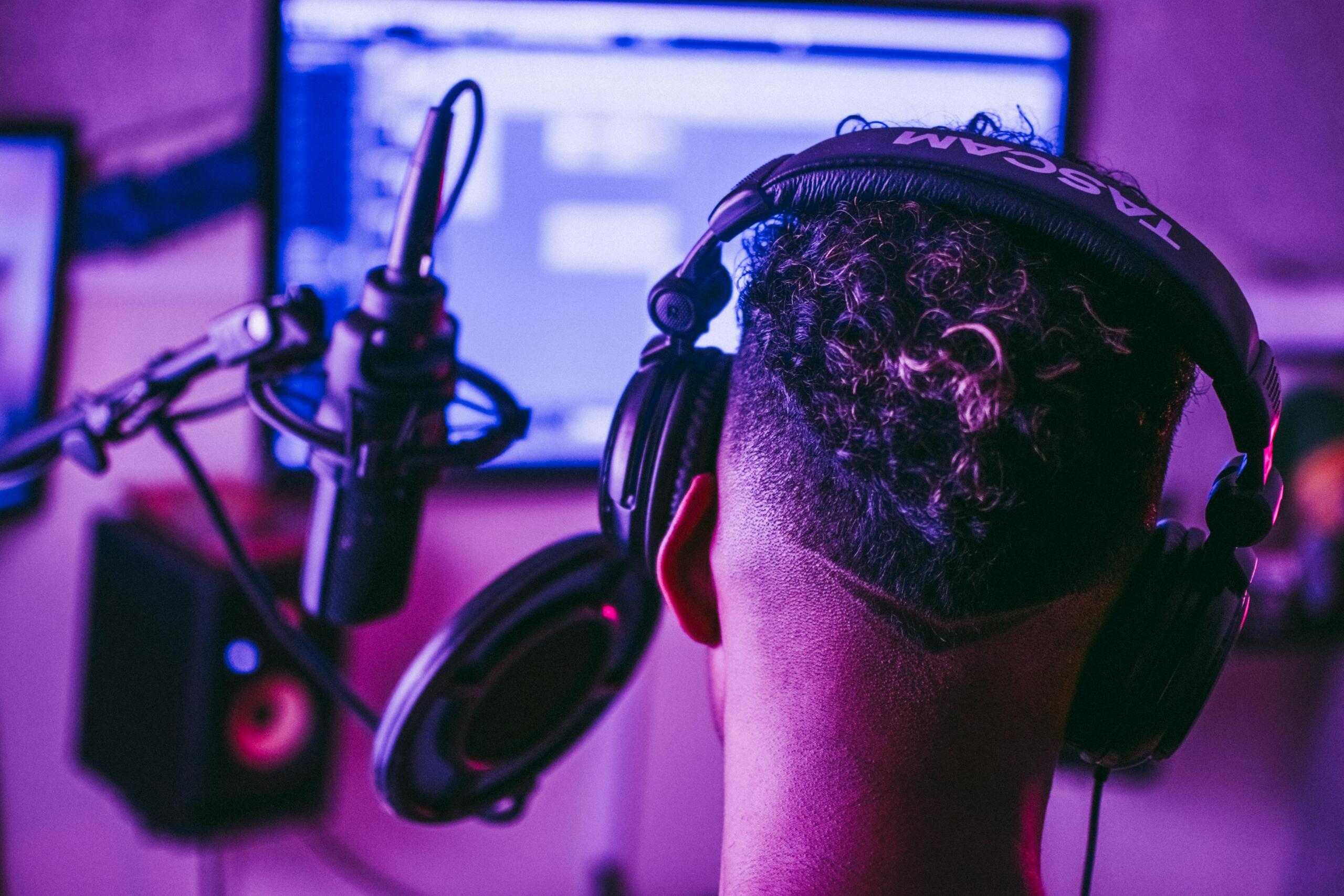 Person wearing headphones in a recording studio, focused on audio production