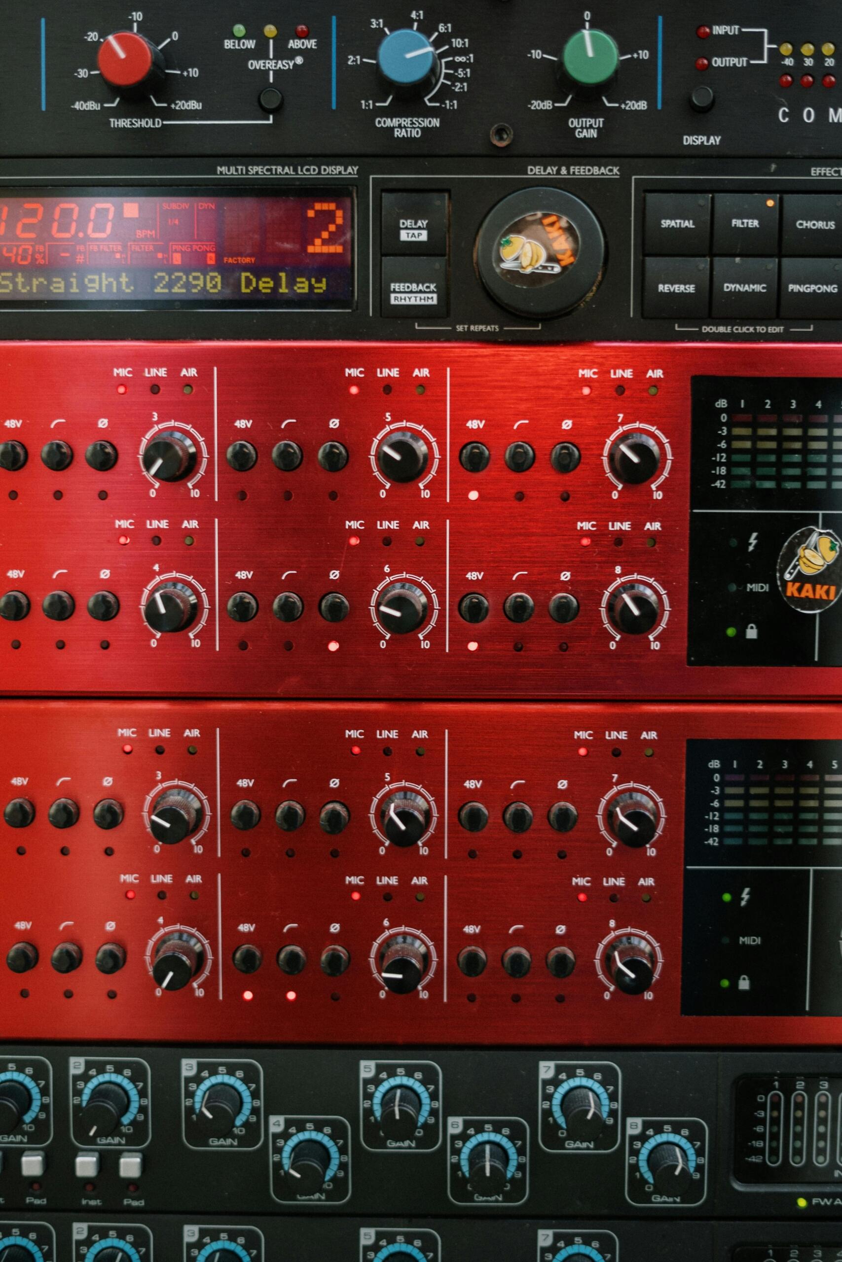 Close-up of a red and black audio mixer with various knobs and sliders