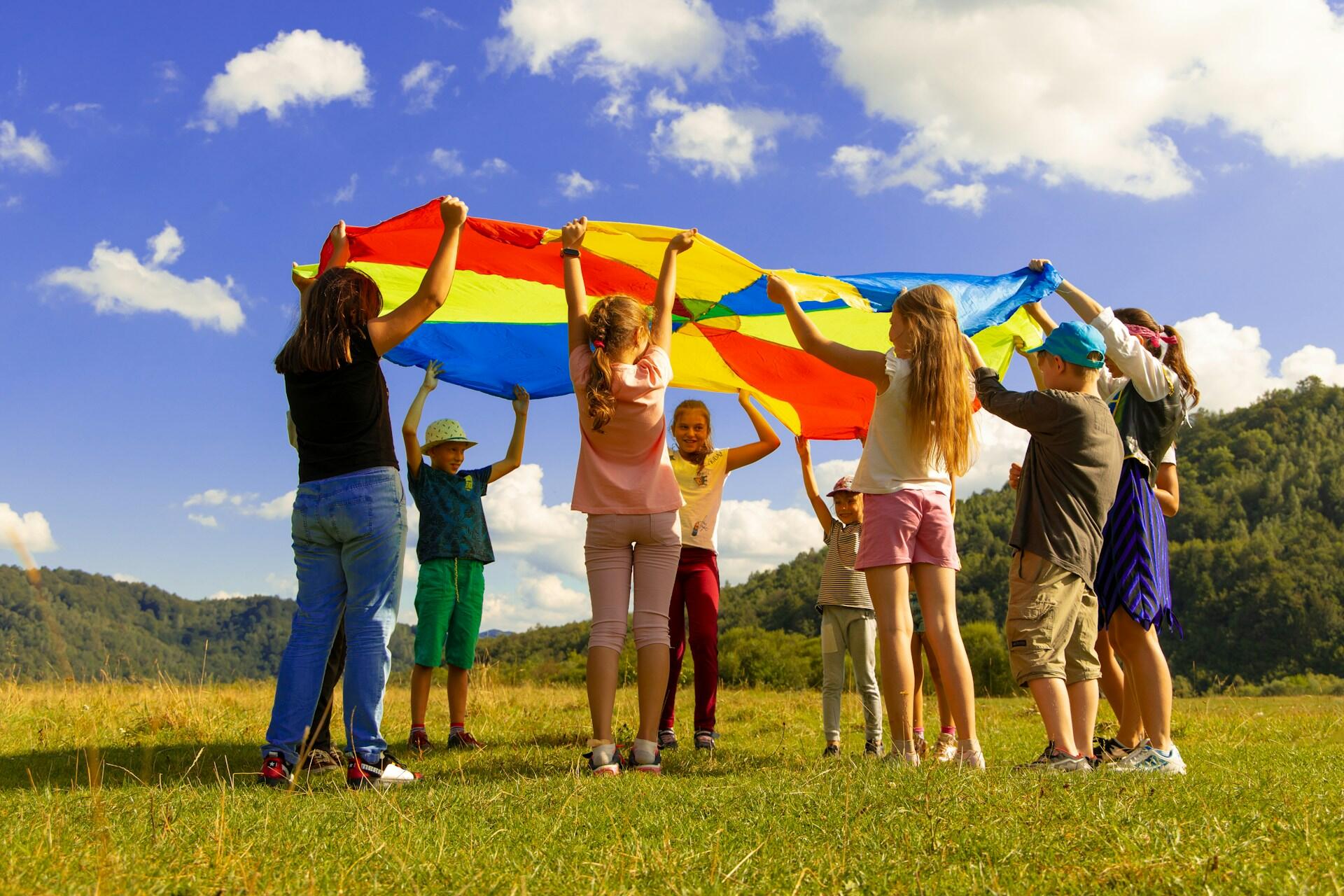 Kids holding up a parachute outside.