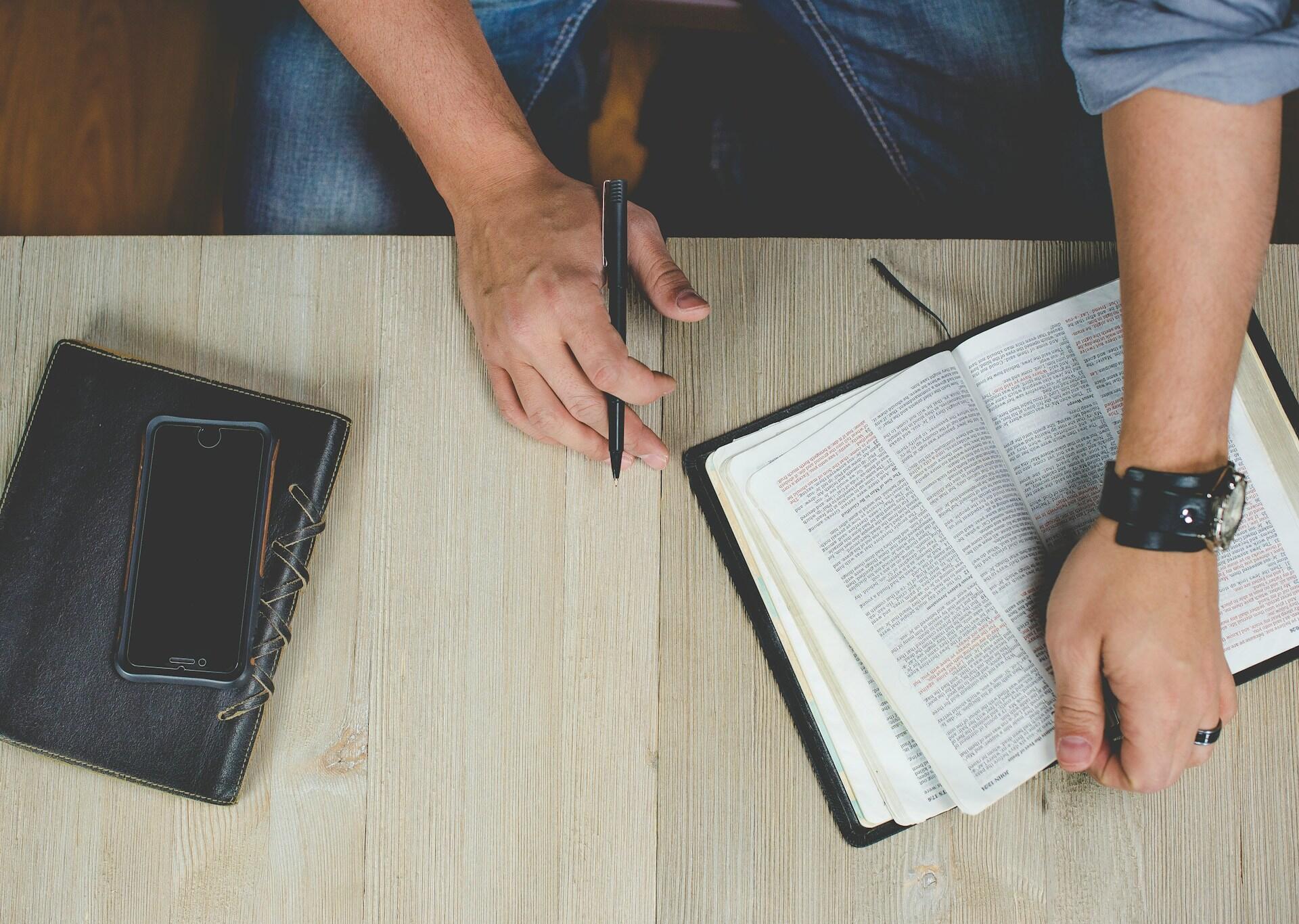 A man reading a book and taking notes.