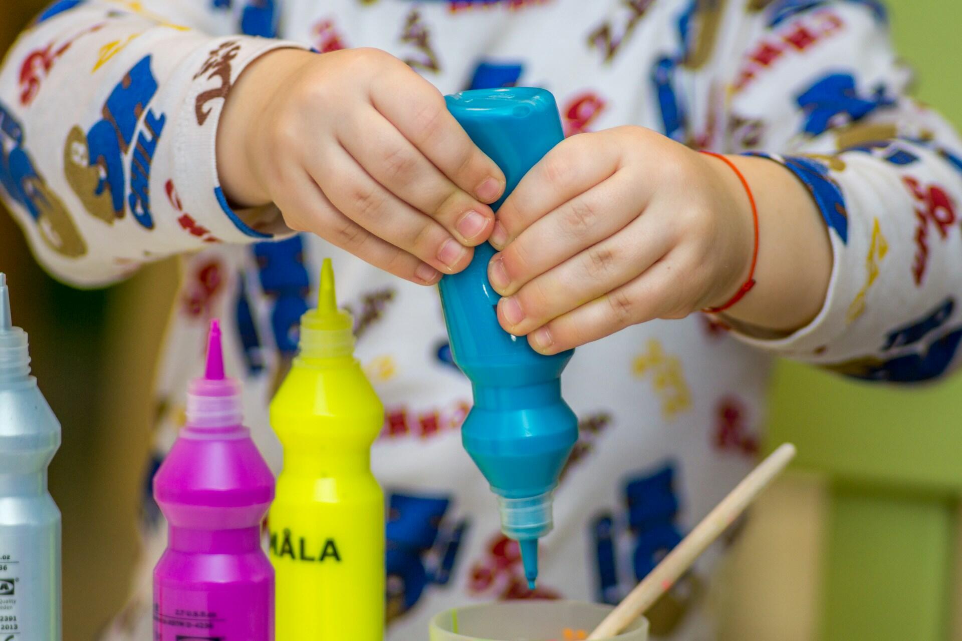 Child holding paint bottle.