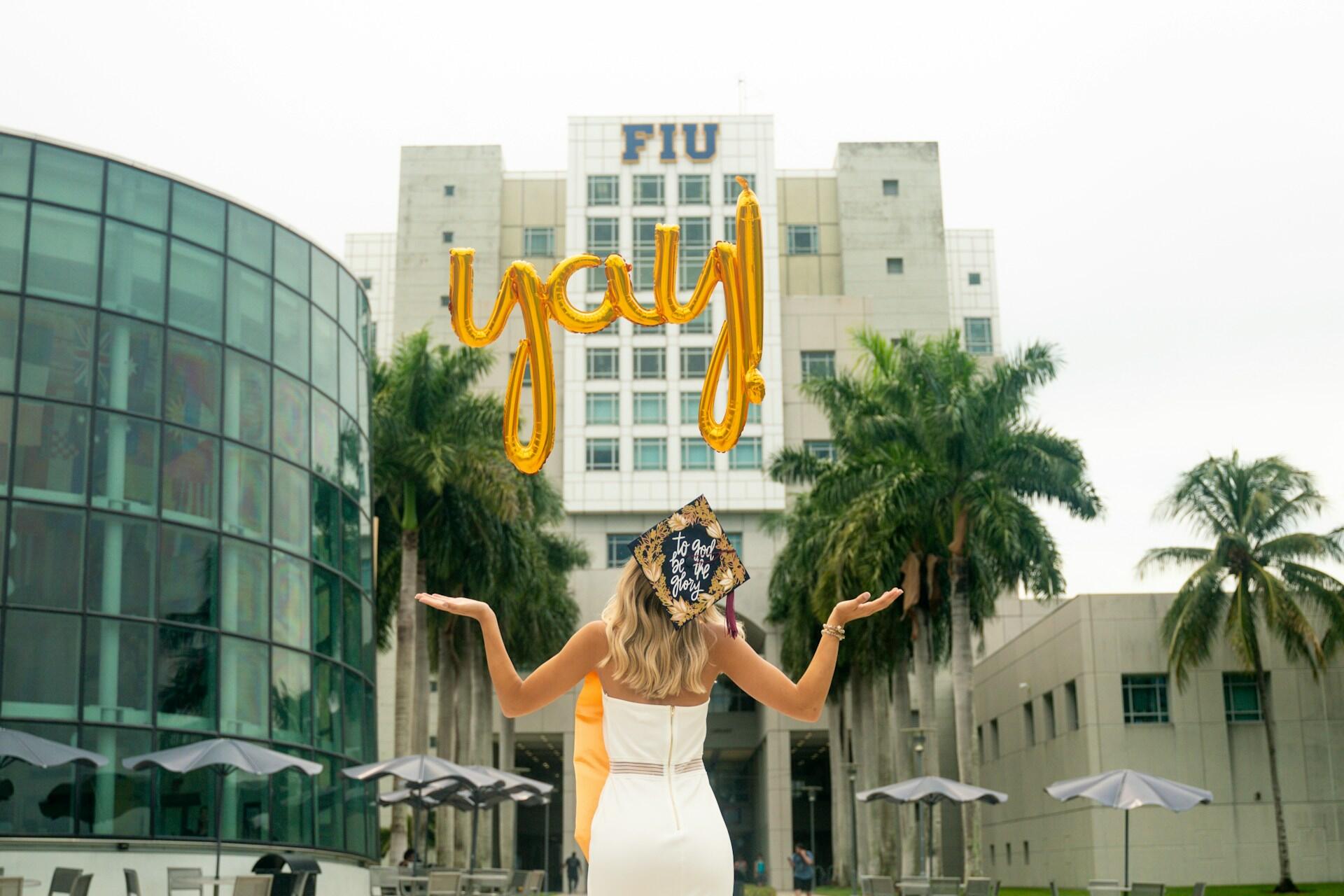 A graduate from FIU facing the university building.
