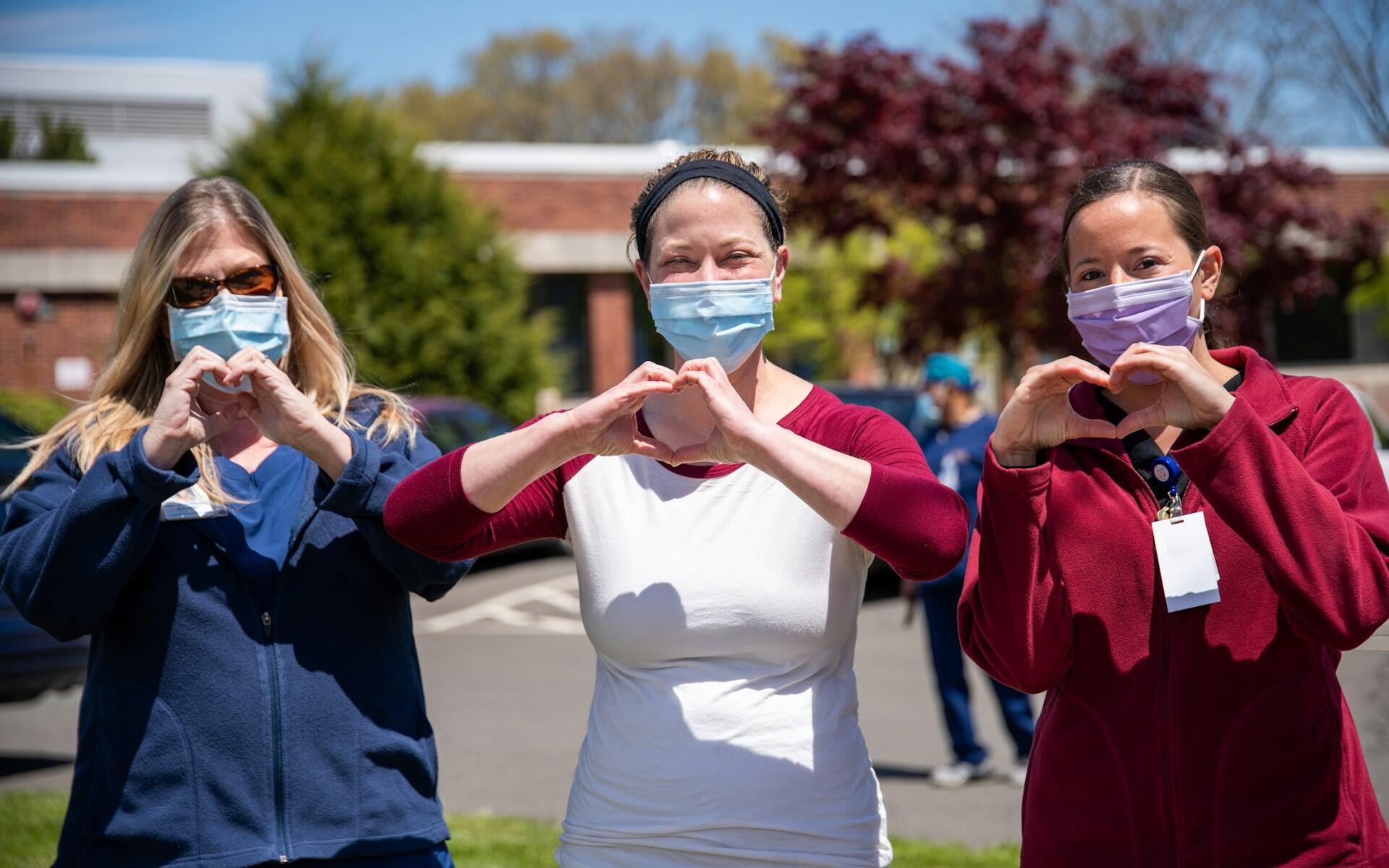 Three powerful nurses making hearts with their hands.