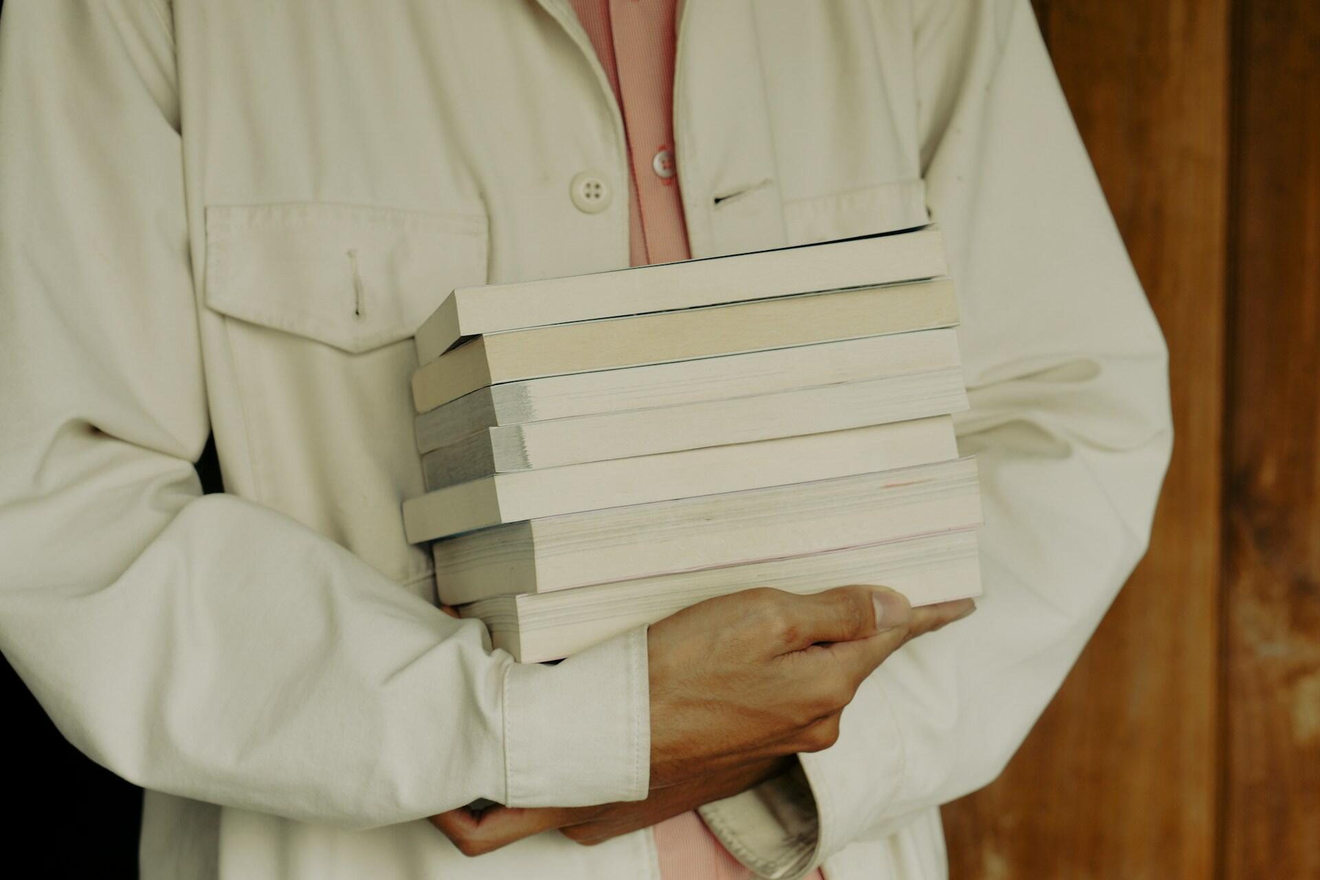A nursing student holding a stack of books.