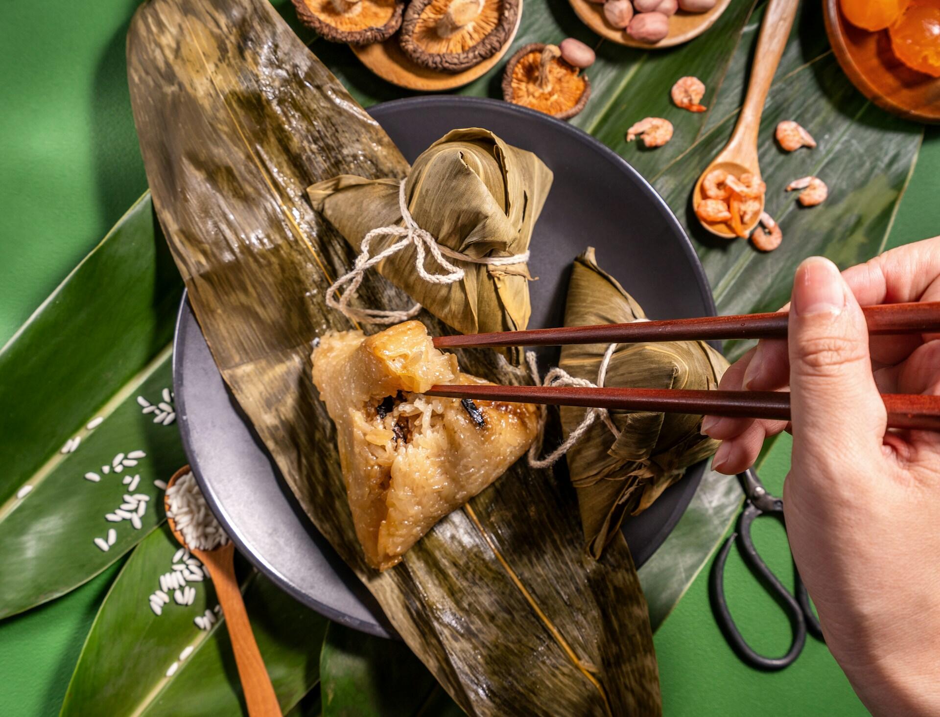 Someone eating Zongzi out of a bamboo leaf.