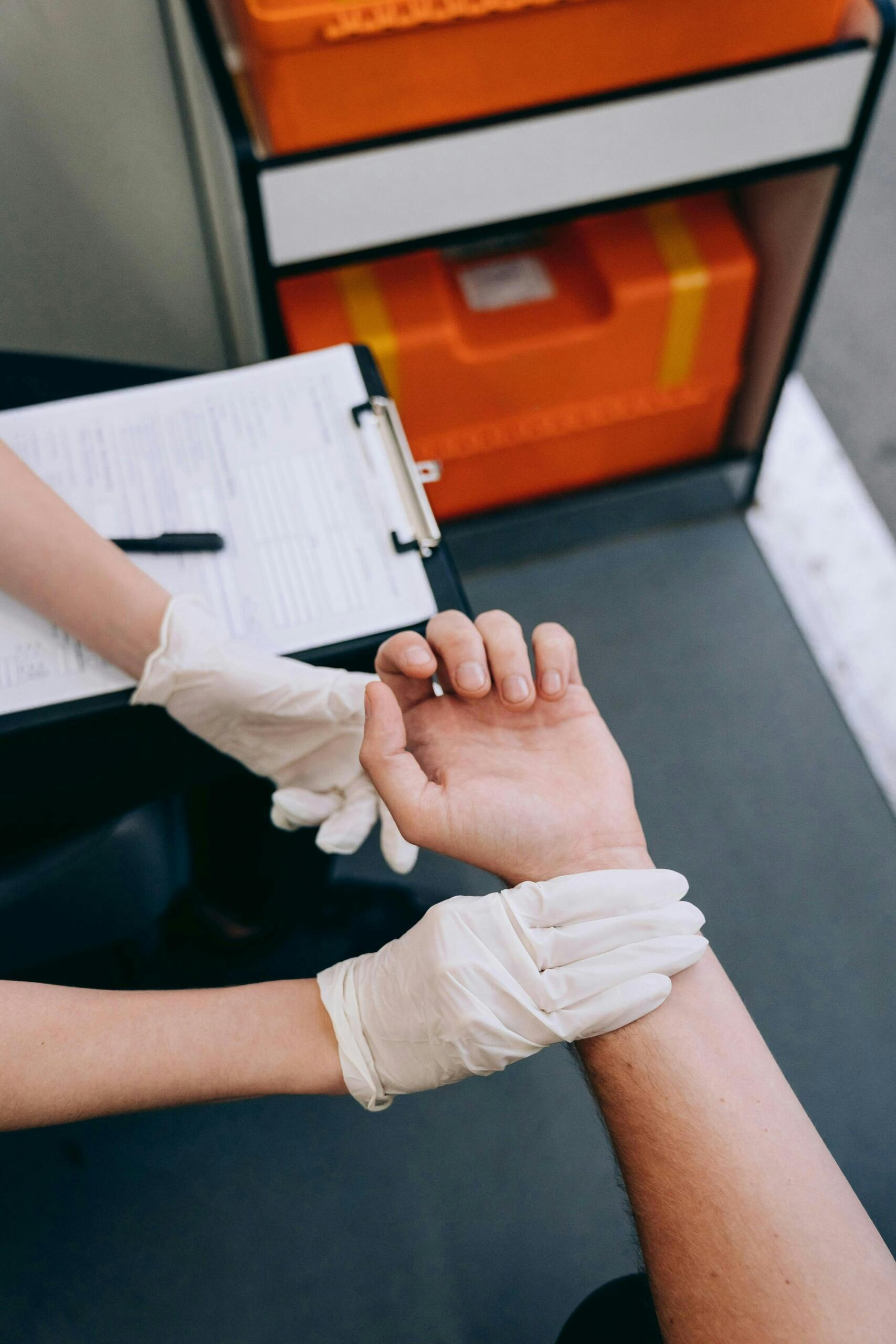 Gloved hands of a medic tending to a patient's arm.