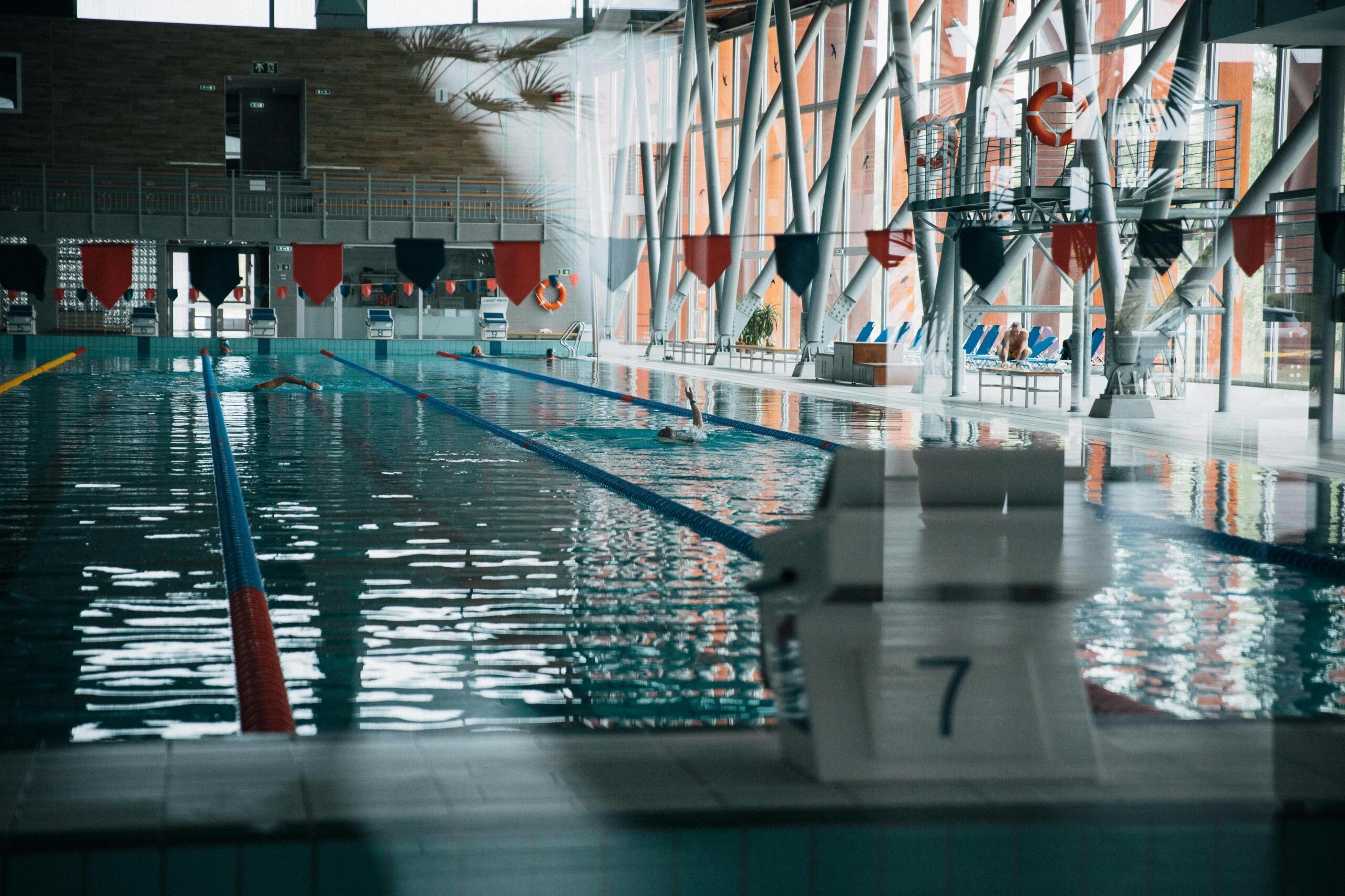 A jumping block at the edge of a rippled swimming pool inside a modern indoor facility.