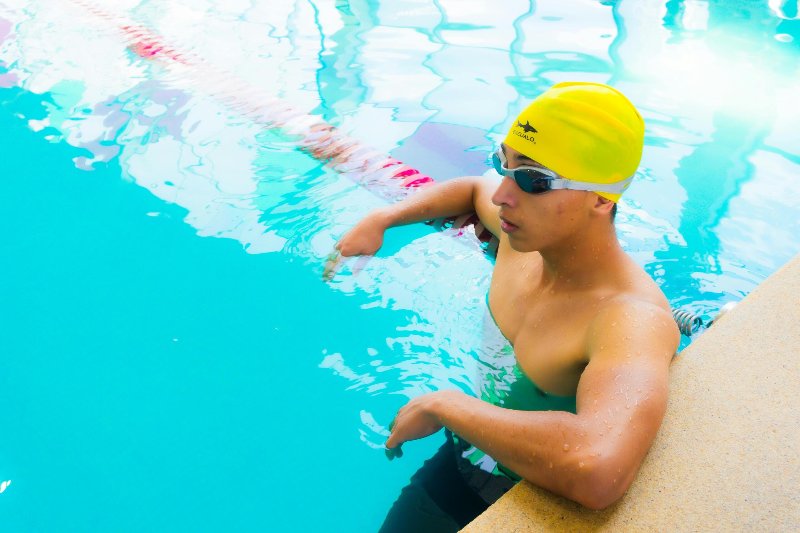 A man sitting at the edge of a swimming pool.