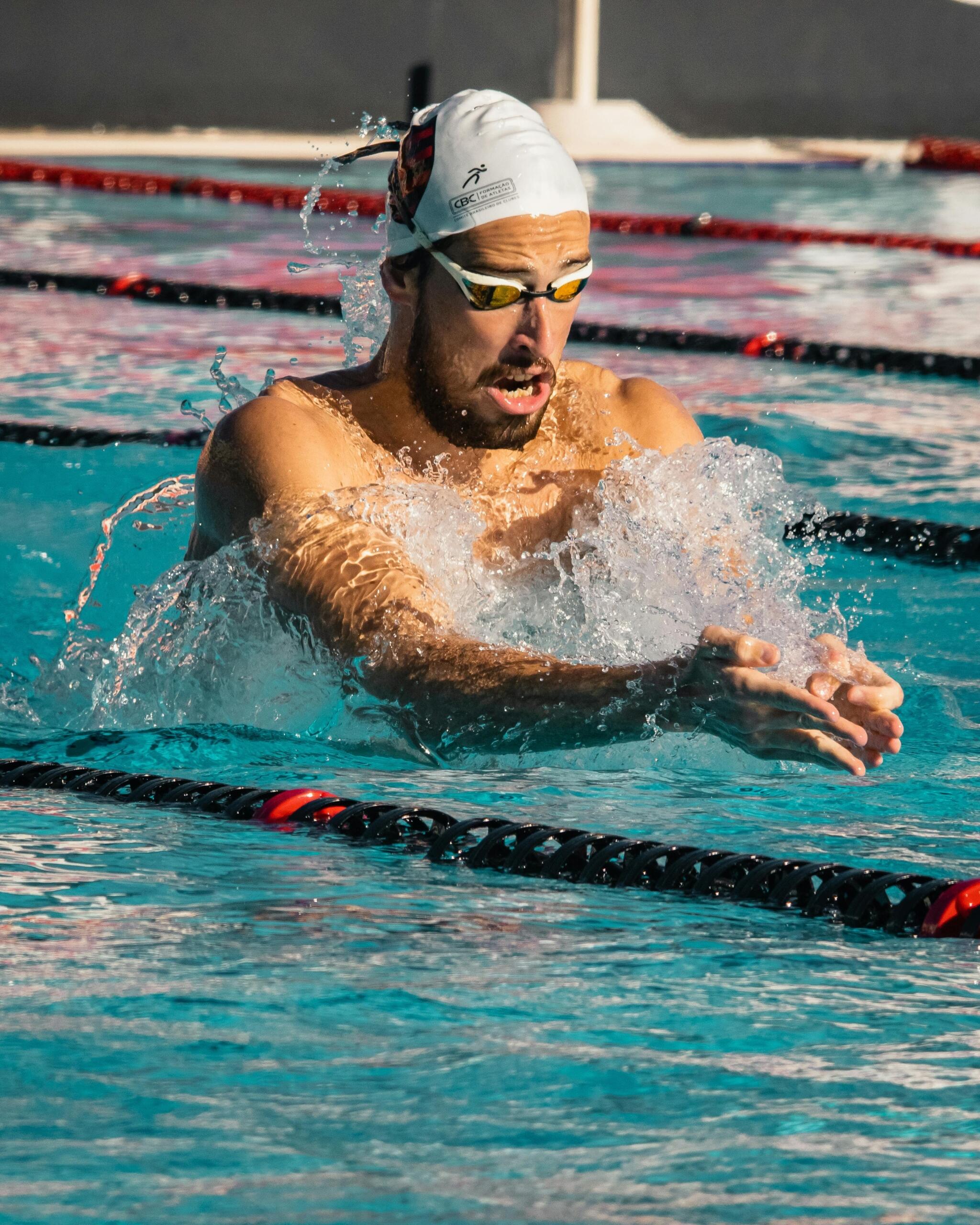 A man practicing swimming strokes in a clear blue pool.