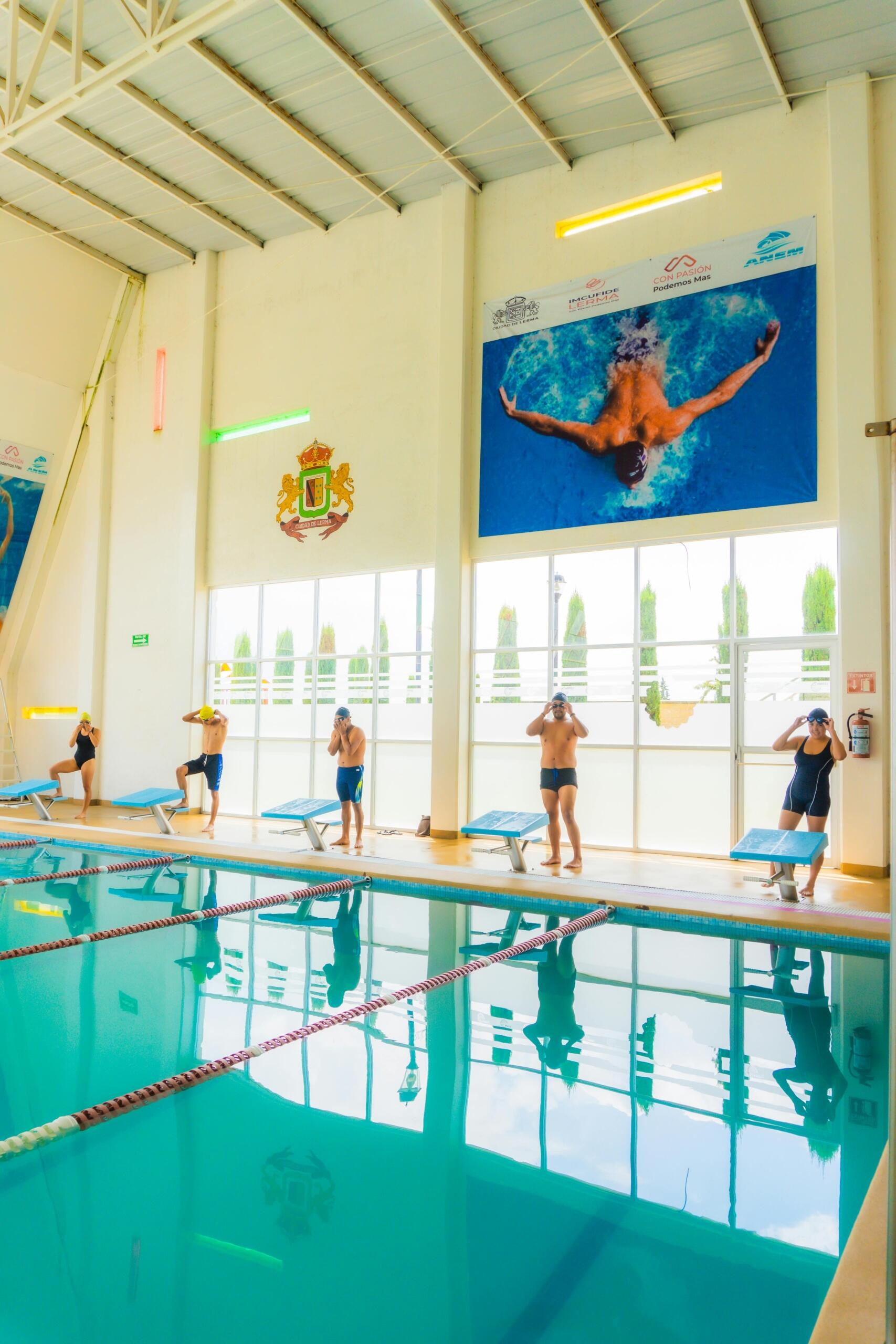 A group of men and women gathered around and in a swimming pool, engaged in a swimming lesson or water activity.