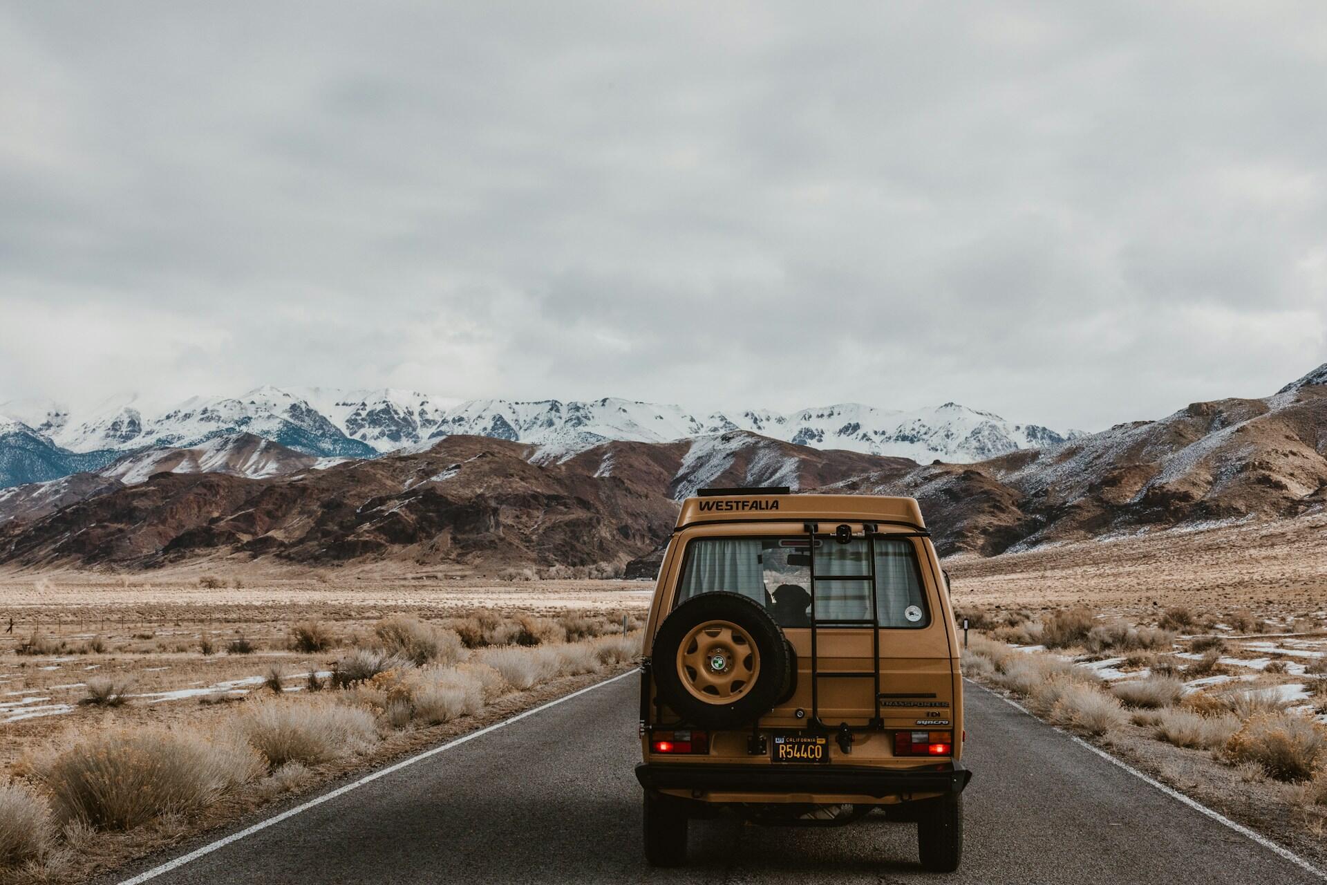 A Westfalia on a road surrounded by mountains.