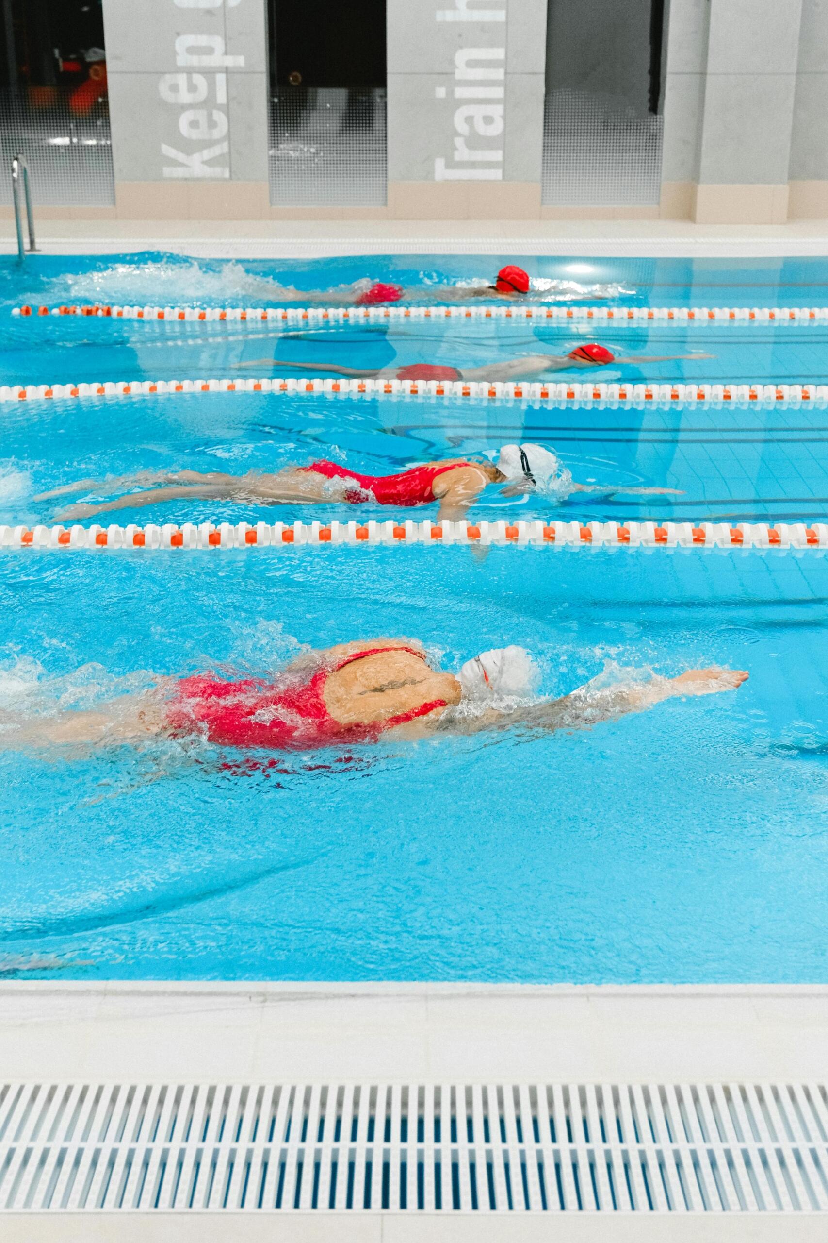Multiple swimmers practicing in designated lanes of an indoor swimming pool.