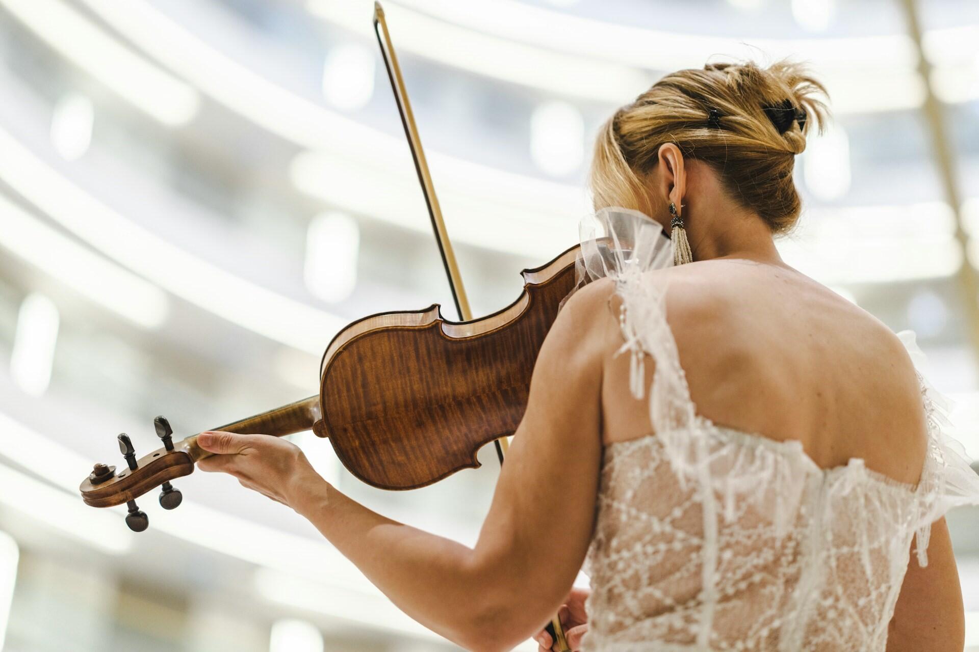 A violinist performing in a white dress.