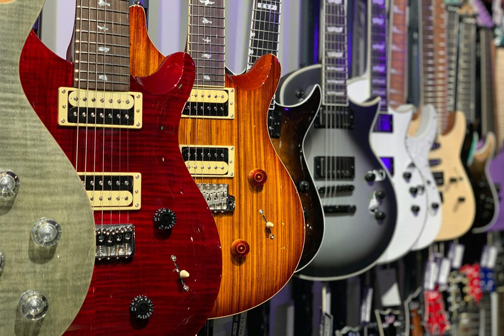 A bunch of electric guitars hanging up in a store.