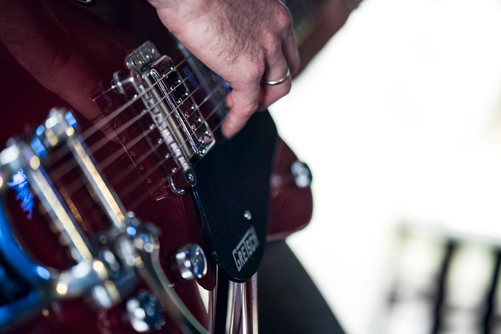 A closeup of a person playing a Gretsch guitar.