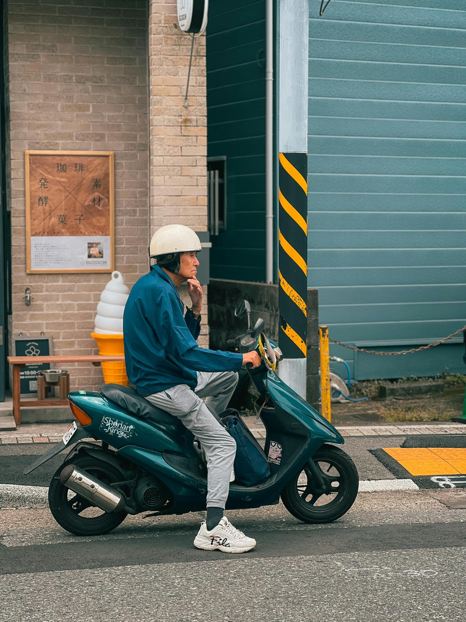 Man on a scooter waiting at a city intersection.