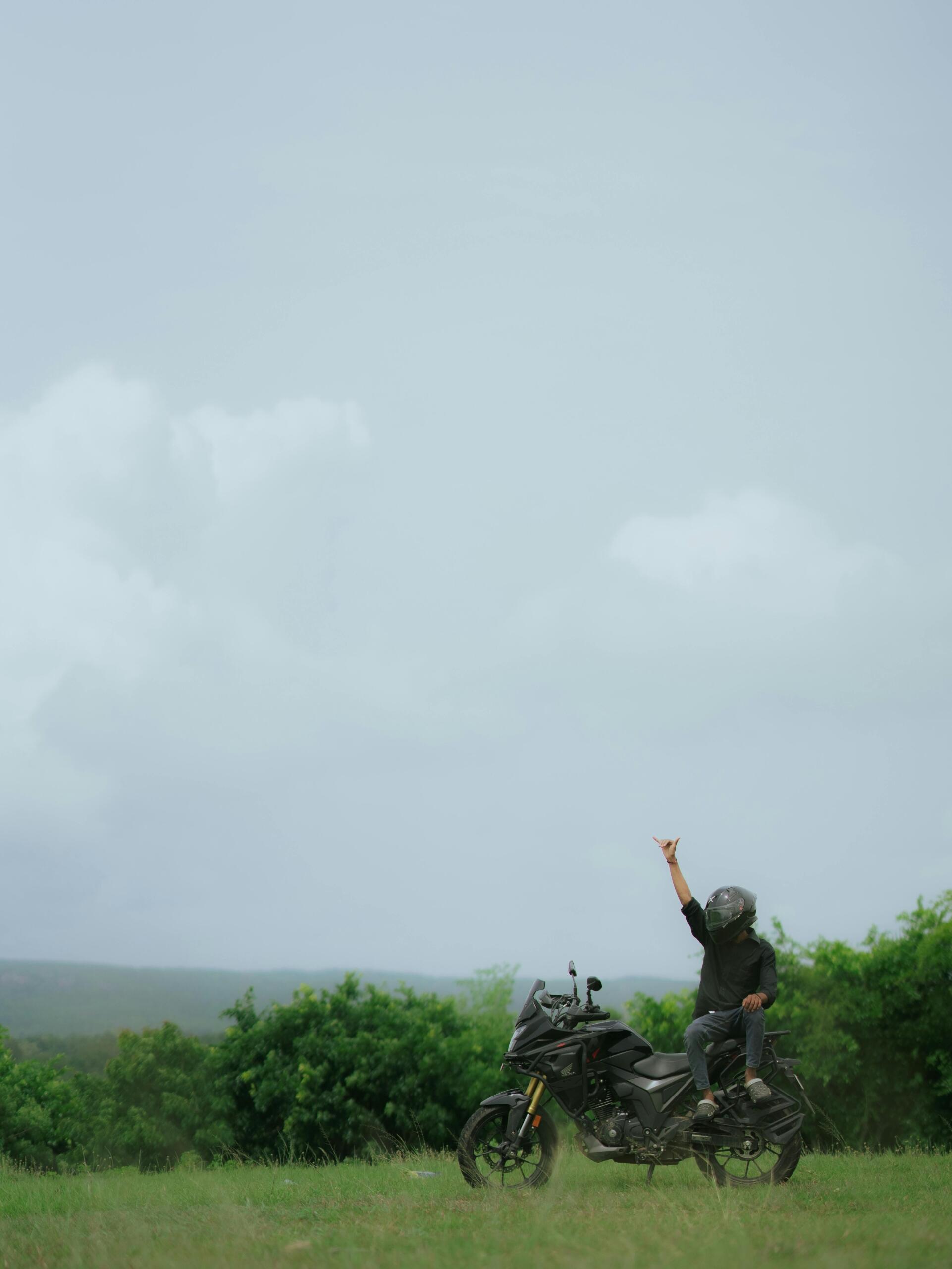 Motorcyclist sitting on a bike, admiring a scenic outdoor landscape.