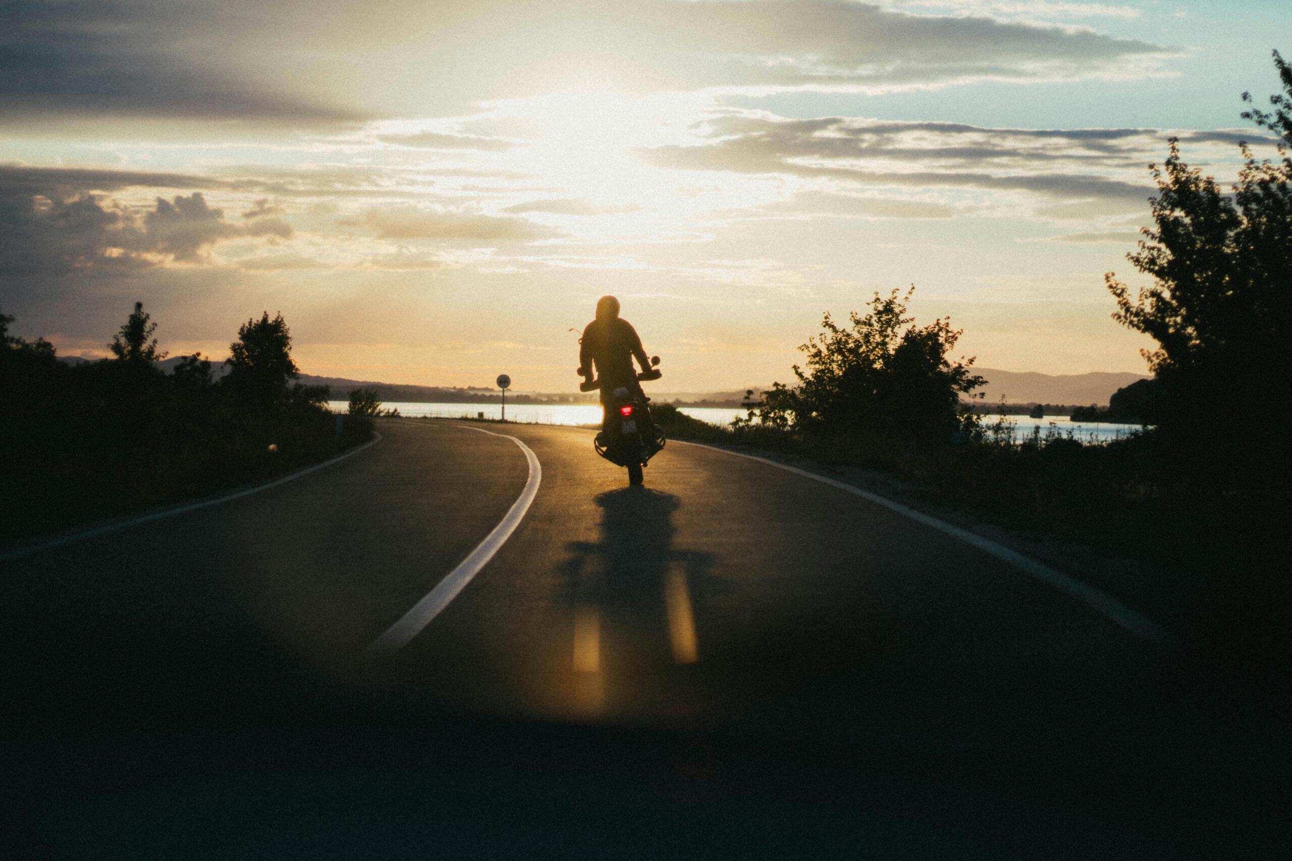 Motorcyclist riding on an open road during golden hour.